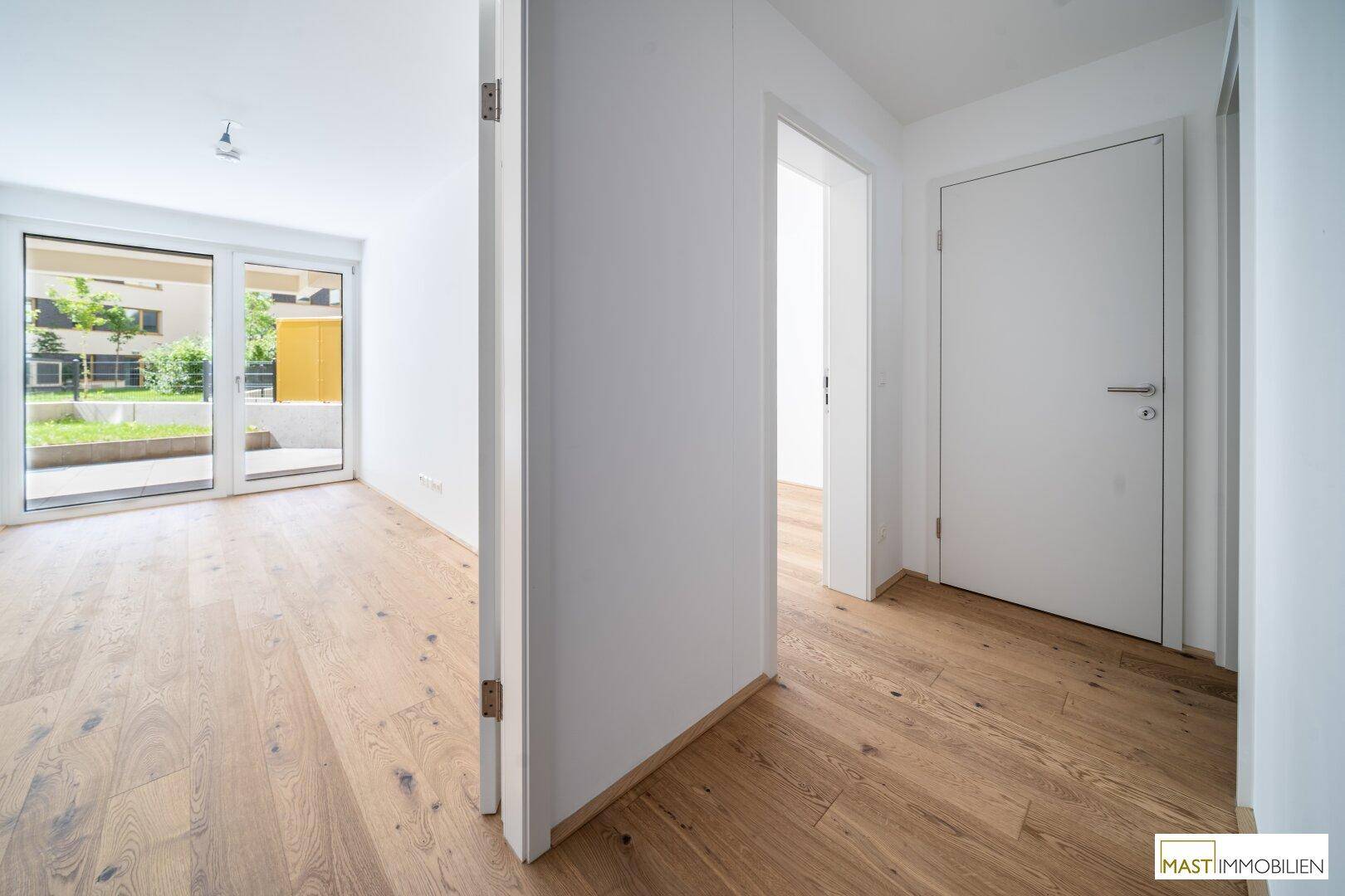 Heller Flur mit Holzboden, der zu weiteren Räumen und dem Wohnbereich führt.