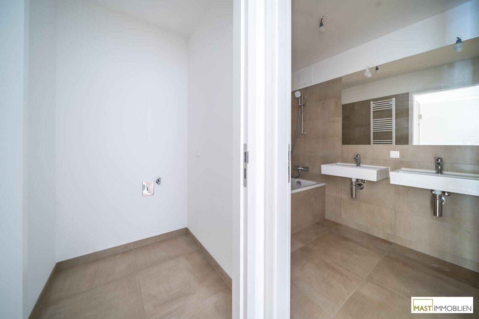 Modernes Badezimmer mit beigefarbenen Fliesen, Doppelwaschbecken und Badewanne.