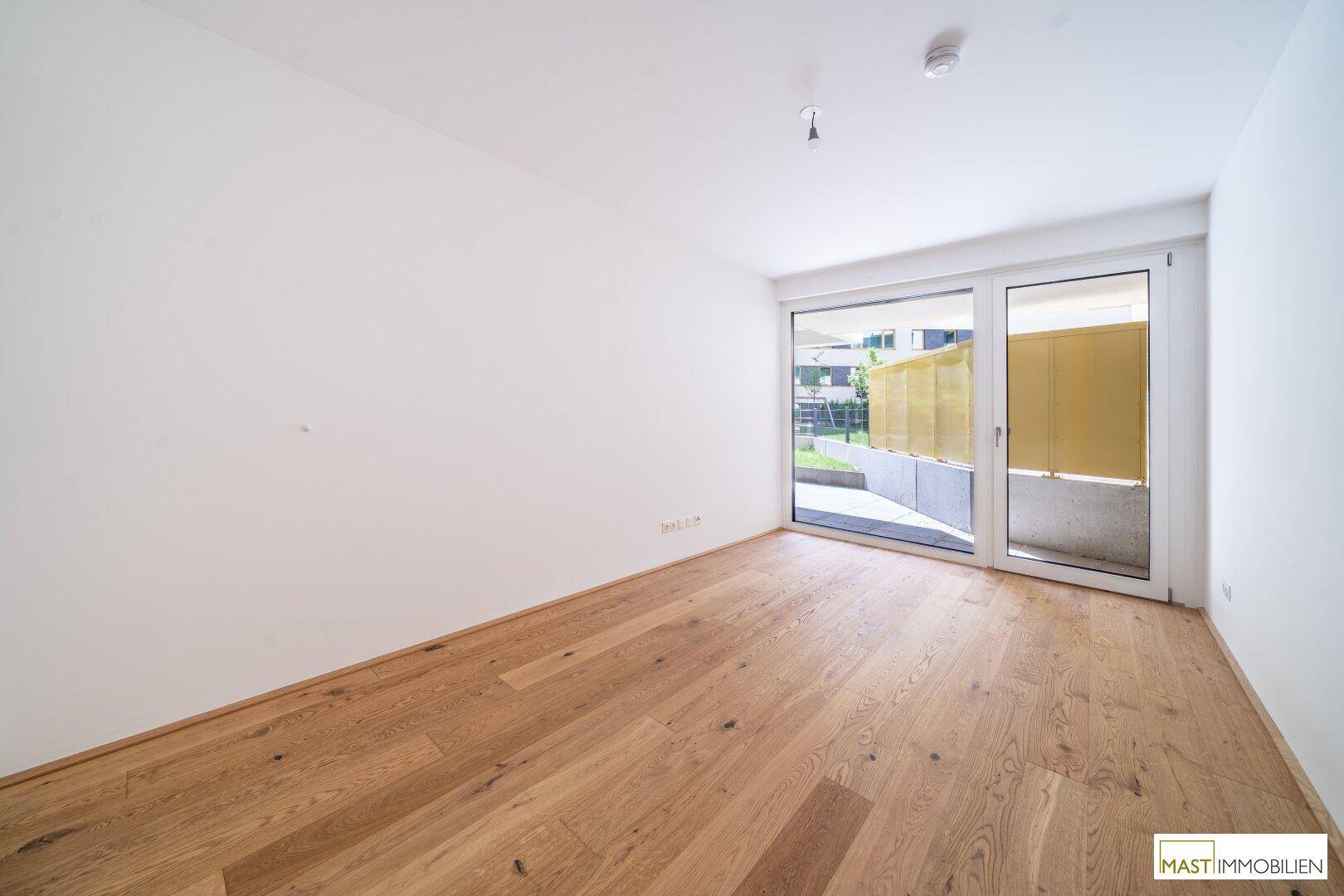 Helles Schlafzimmer mit Holzboden und direktem Zugang zur Außenterrasse.