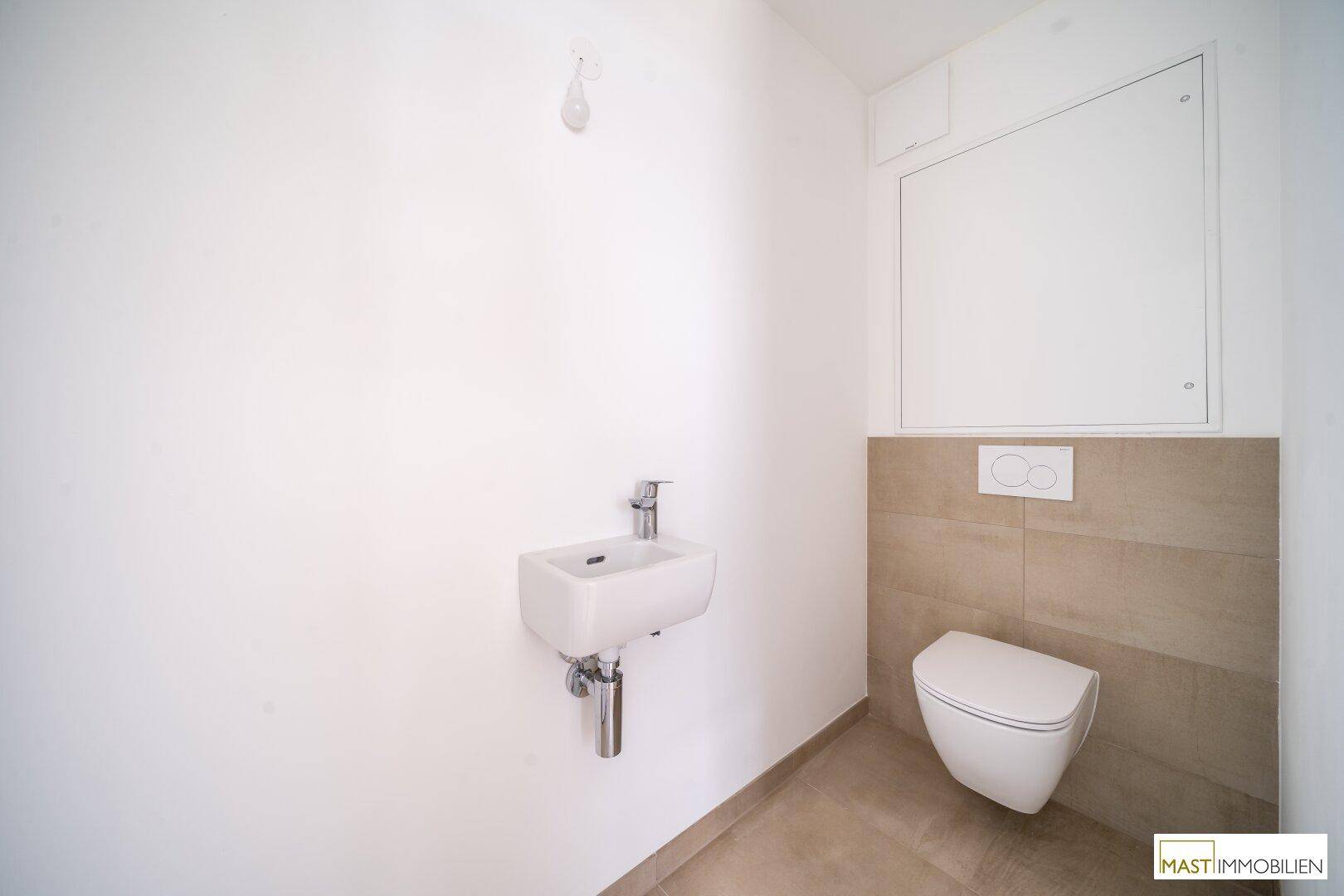 Modernes Gäste-WC mit wandhängender Toilette und kleinem Waschbecken, teilweise gefliest.