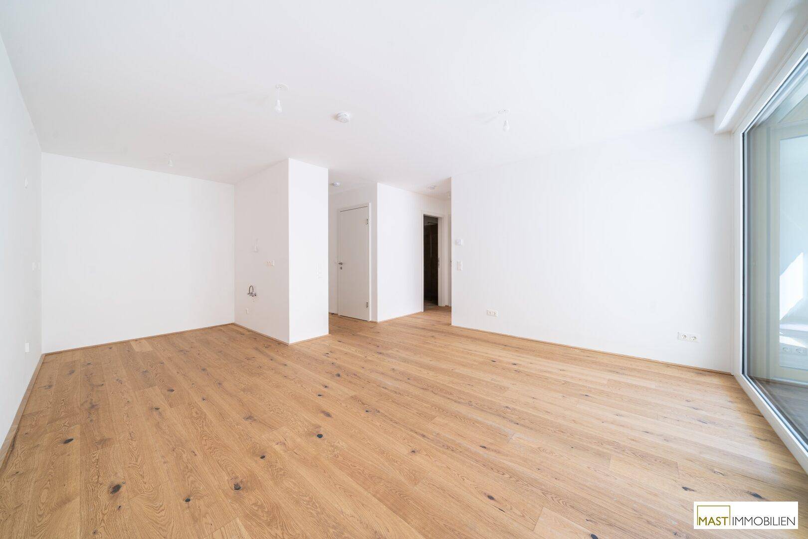 Geräumiges, leeres Zimmer mit hellem Parkettboden und weißen Wänden, bereit zur individuellen Gestaltung.