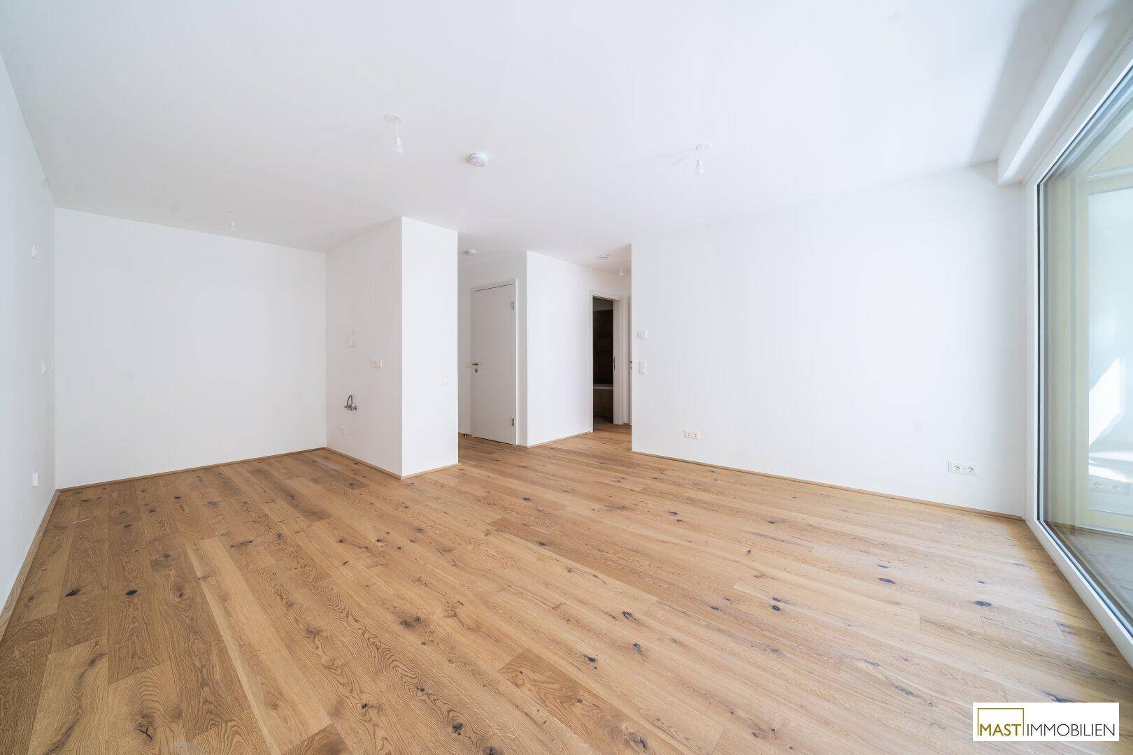 Geräumiges, helles Zimmer mit Parkettboden und Zugang zu einem Außenbereich, vielseitig nutzbar.