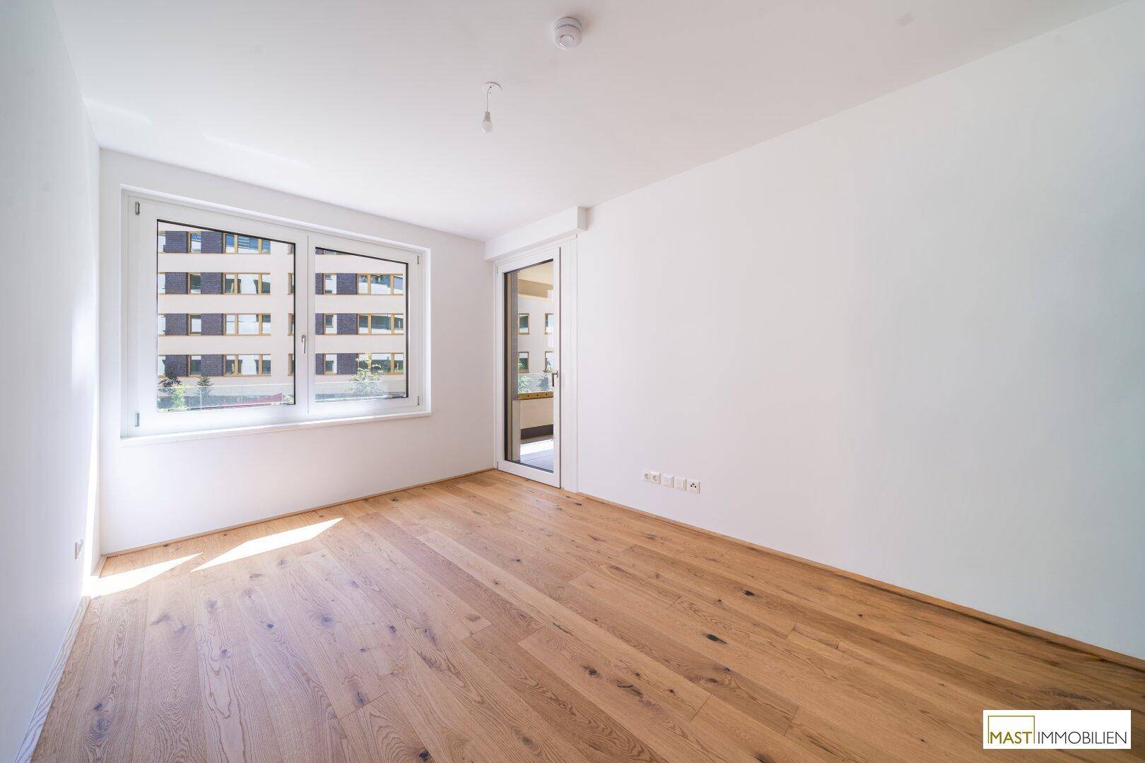 Lichtdurchflutetes Zimmer mit Parkettboden und großem Fenster, bereit zur individuellen Gestaltung.