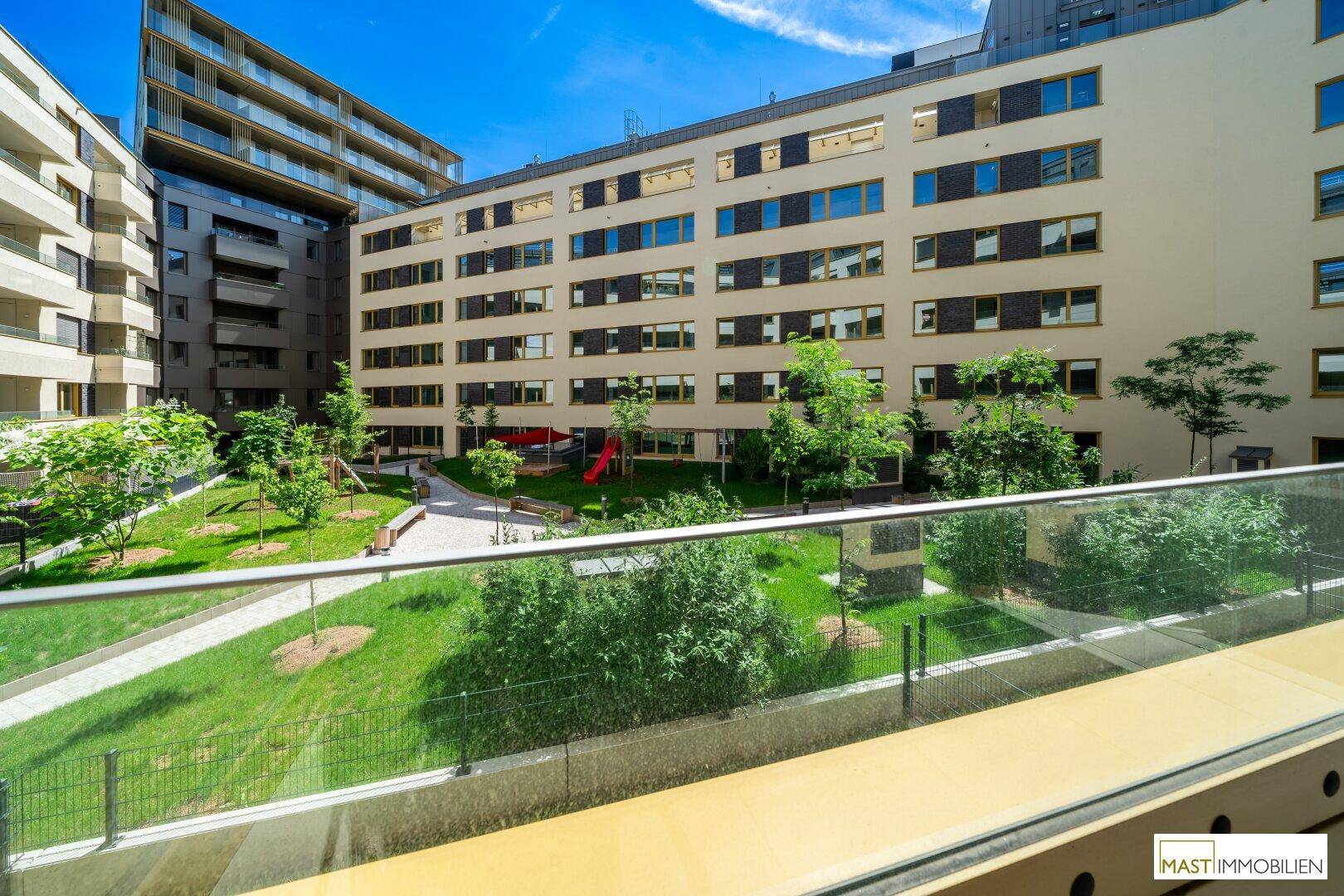 Blick auf den begrünten Innenhof mit Spielplatz und modernen Wohngebäuden im Hintergrund.