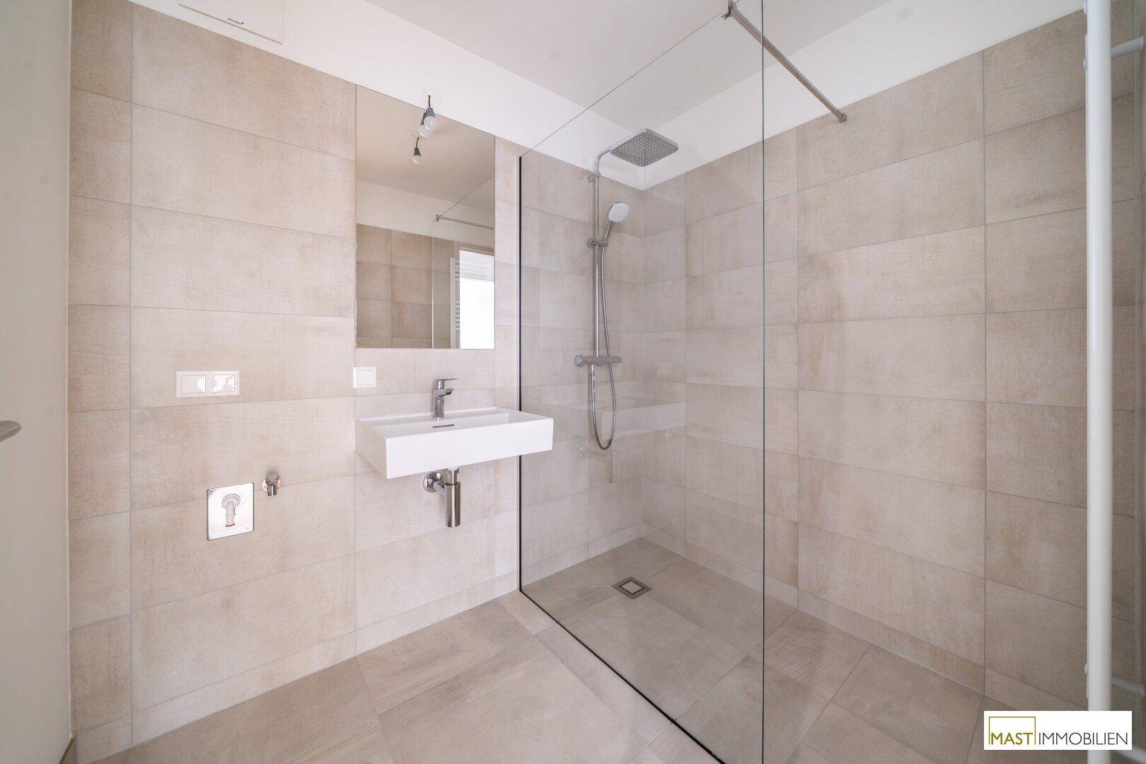 Geräumige, begehbare Dusche mit Glaswand und modernen Fliesen im Badezimmer.