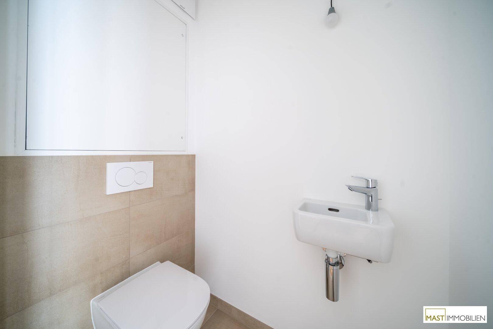 Modernes Gäste-WC mit wandhängender Toilette und kleinem Handwaschbecken in schlichtem Design.