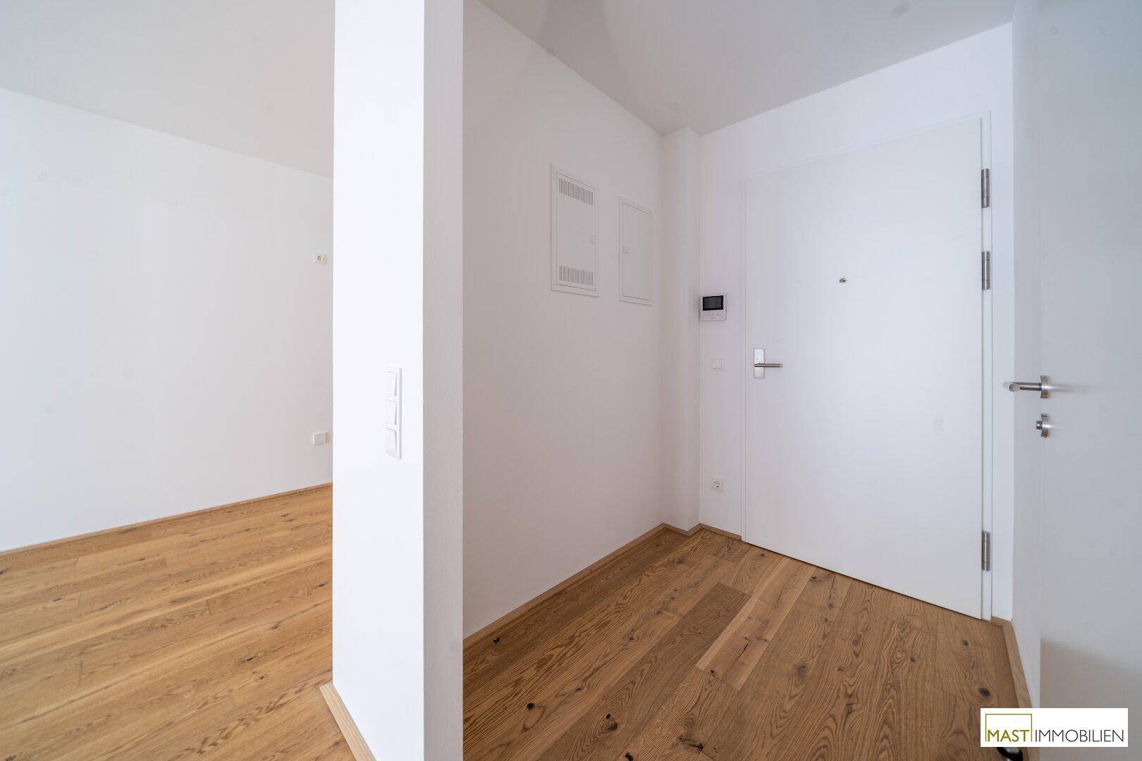 Heller Eingangsbereich mit Holzboden und moderner Wohnungstür, bietet einen freundlichen Empfang.