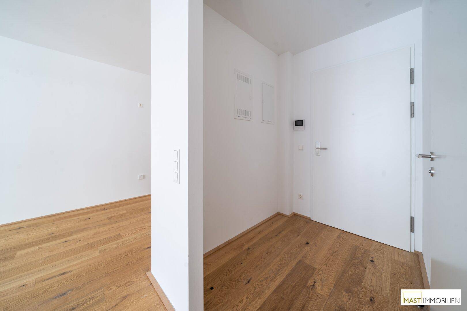 Heller Eingangsbereich mit Holzboden und modernen weißen Türen, einladend gestaltet.