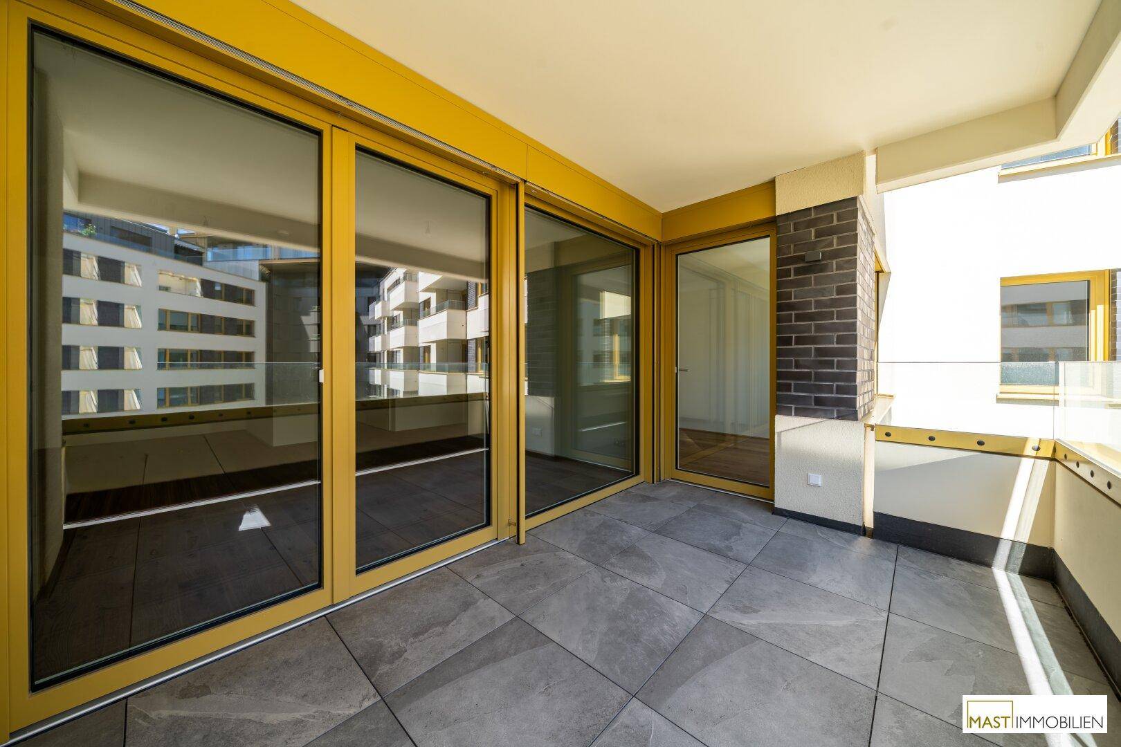 Geräumiger Balkon mit modernen Fliesen und gelben Akzenten, bietet Platz zum Entspannen.