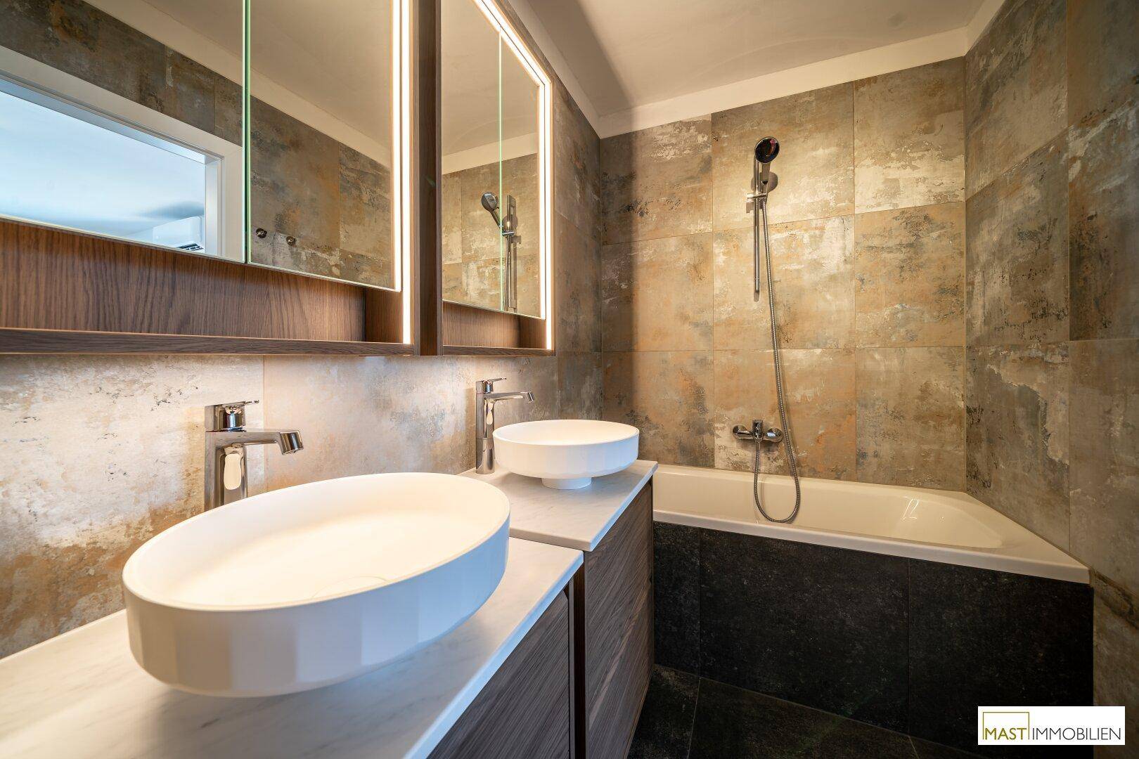 Elegantes Badezimmer mit zwei Aufsatzwaschbecken, Spiegelschrank und einer modernen Badewanne.