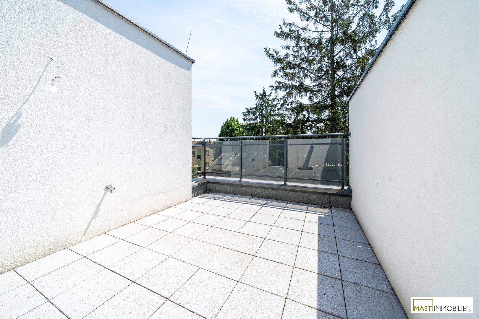 Sonnige Dachterrasse mit modernen Fliesen und Glasgeländer, ideal zum Entspannen im Freien.