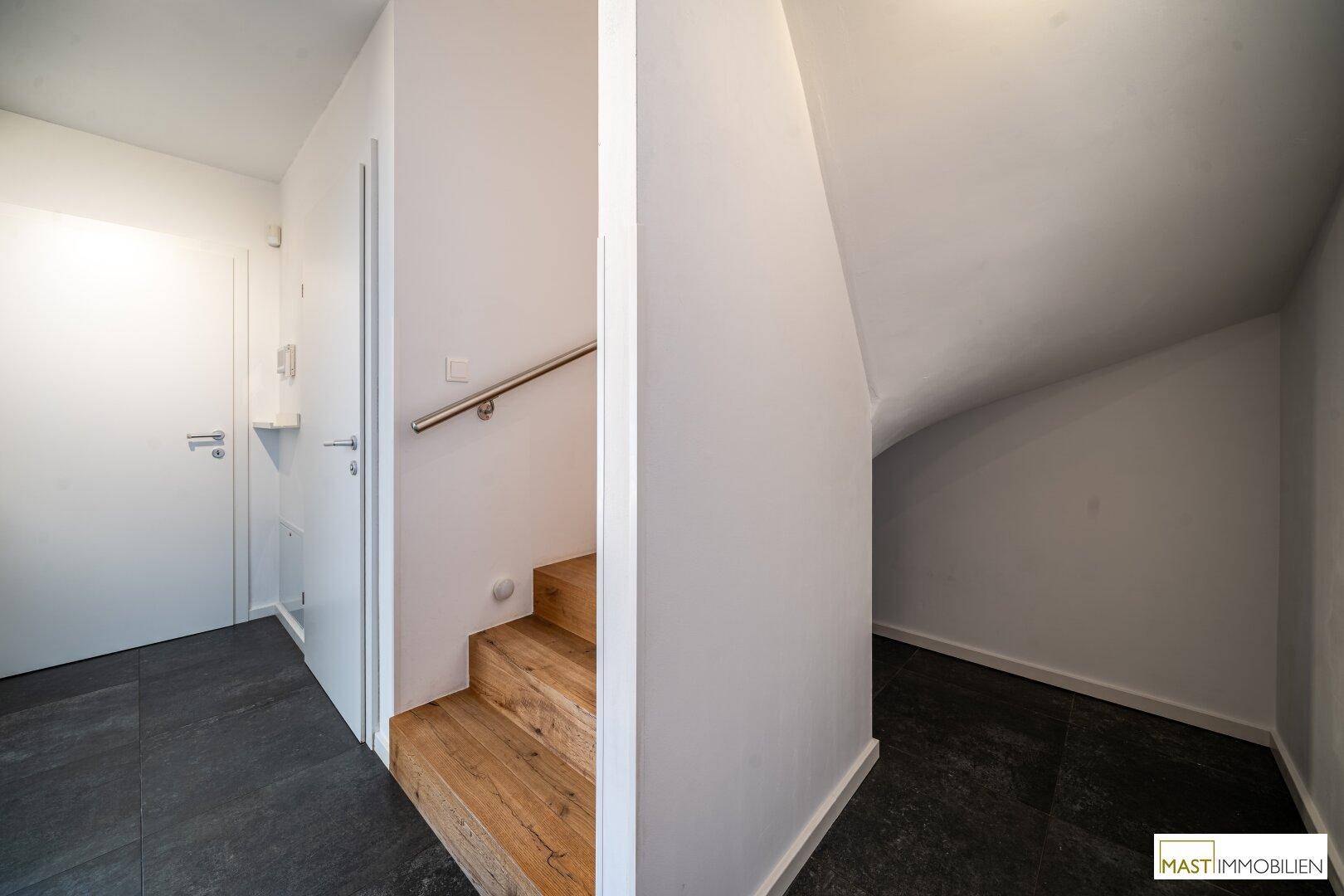 Heller Flur mit Holztreppe und praktischem Stauraum unter der Treppe.