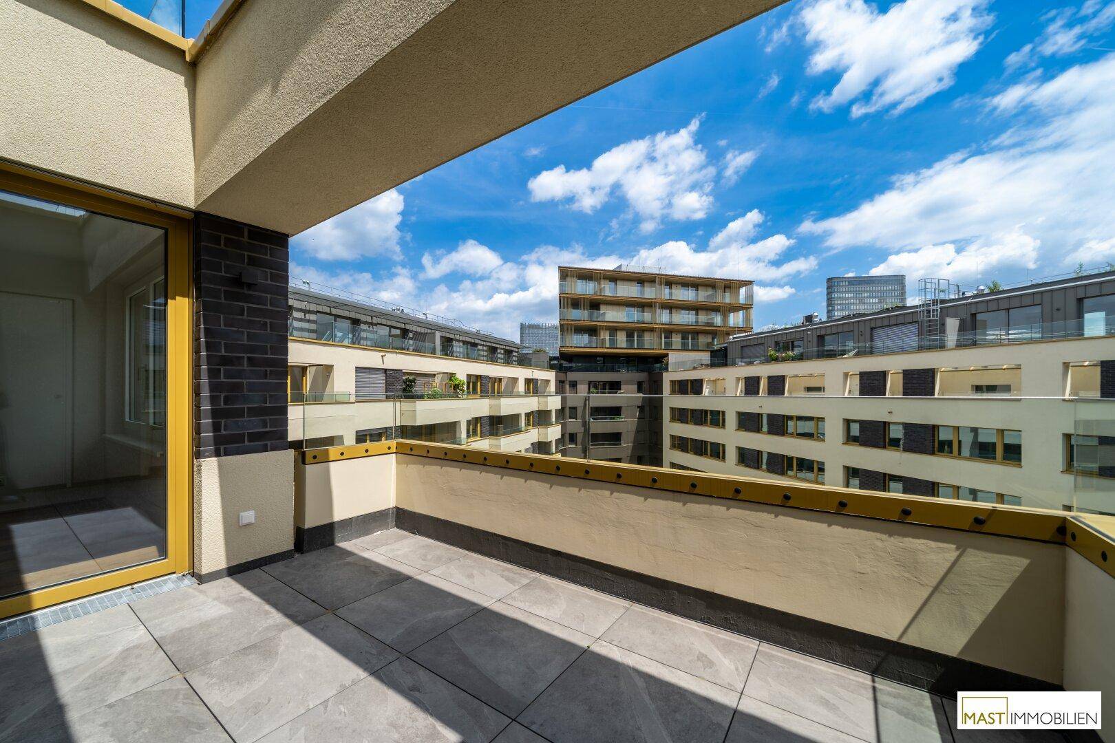 Geräumiger Balkon mit Fliesenboden und Blick auf die umliegenden modernen Gebäude der Wohnanlage.