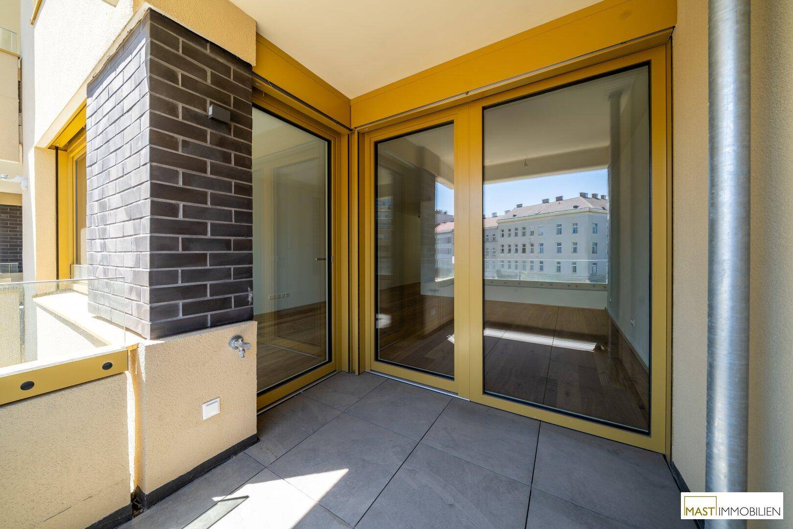 Balkon mit großen Glasfronten, die viel Licht in die Innenräume lassen und einen urbanen Ausblick bieten.