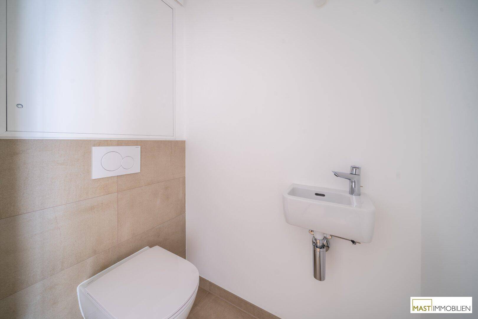 Funktionales Gäste-WC mit wandhängender Toilette und kleinem Waschbecken, in neutralen Farben gehalten.
