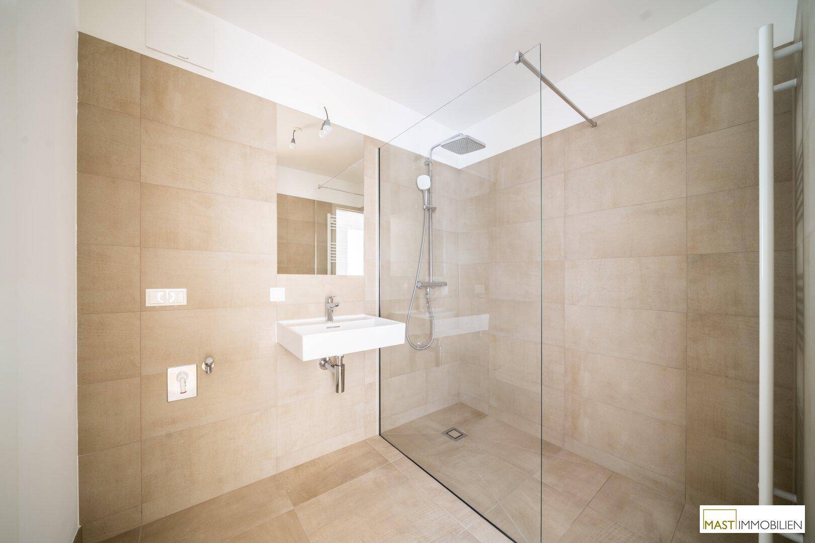 Modernes Badezimmer mit beigefarbenen Fliesen, ebenerdiger Dusche und Einzelwaschbecken.