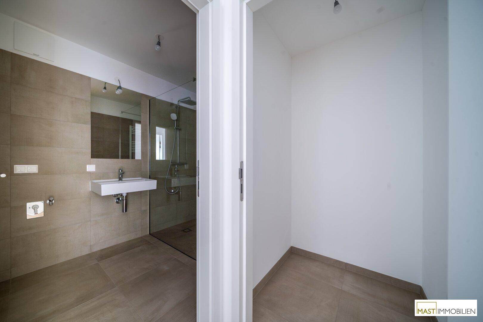 Blick in ein modernes Badezimmer von einem angrenzenden leeren Raum aus.