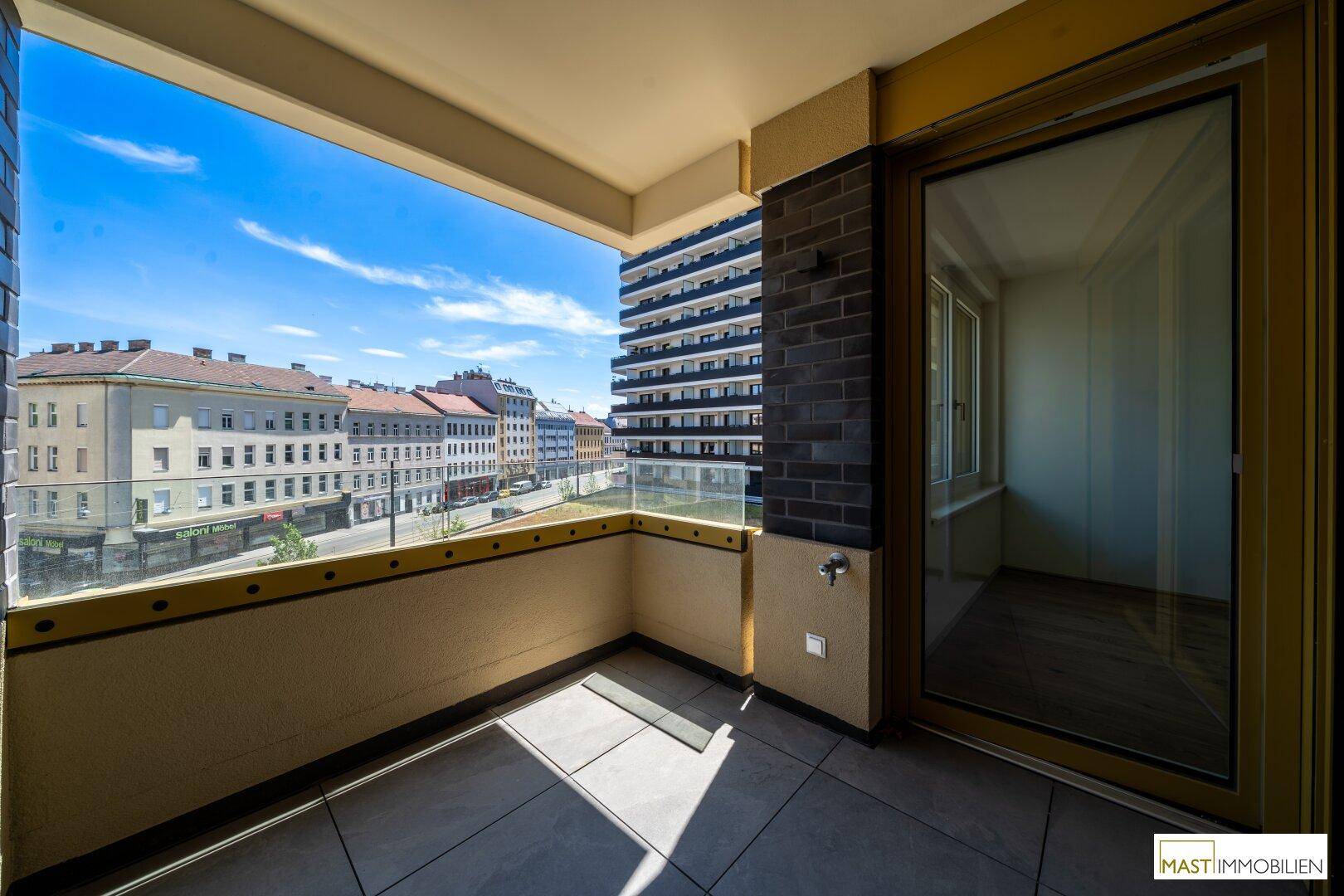Geräumiger Balkon mit Glasbrüstung und Blick auf die umliegende Stadtbebauung.