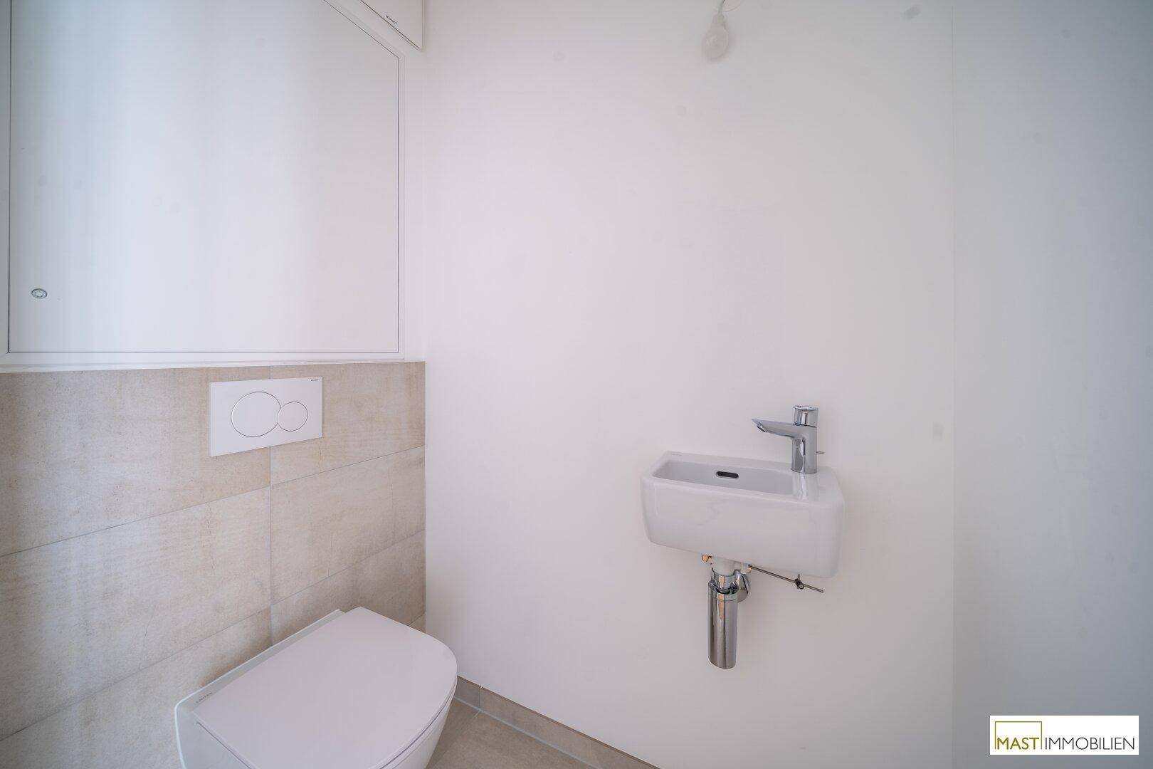 Modernes Gäste-WC mit wandhängender Toilette und kleinem Waschbecken, in hellen Farbtönen gehalten.