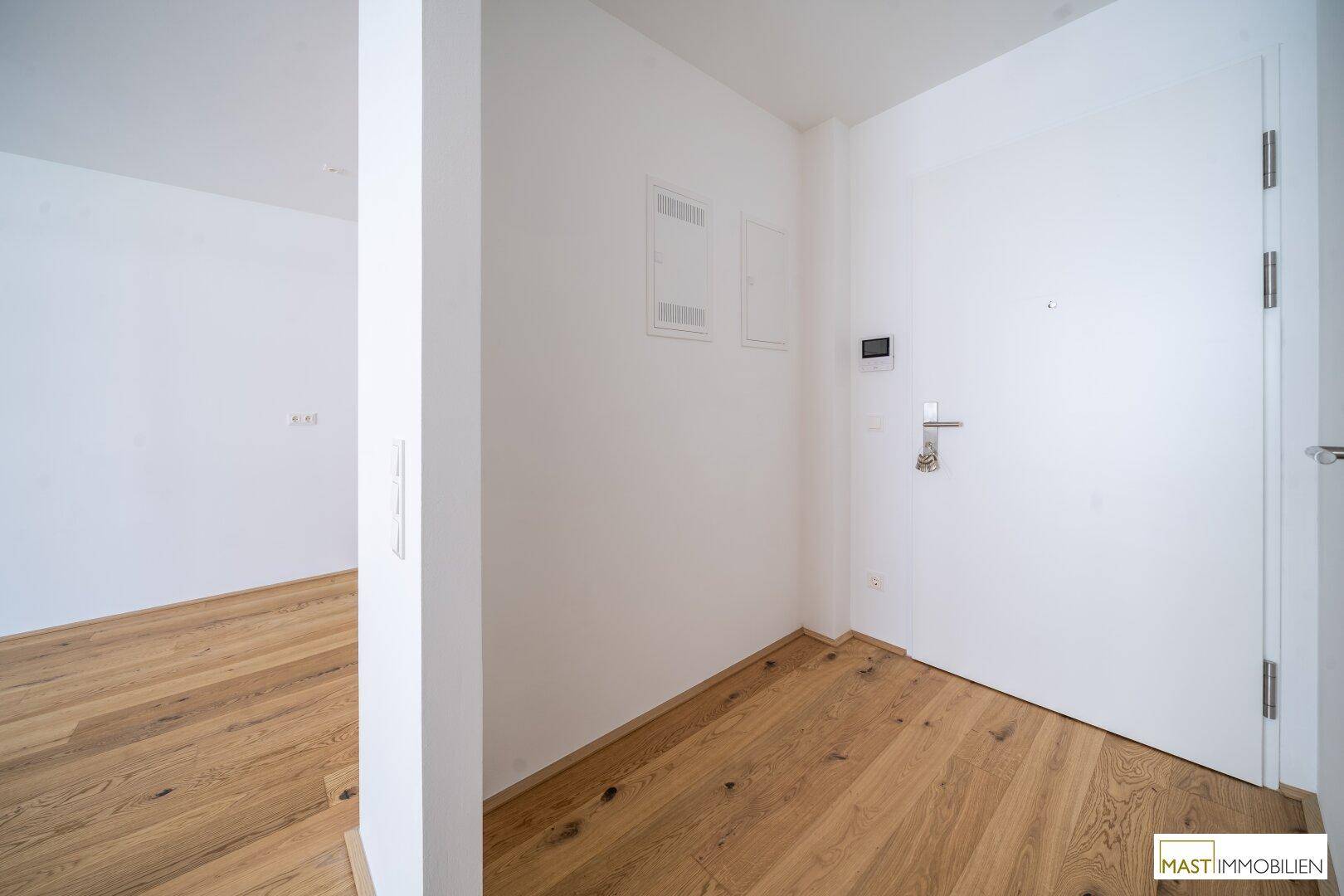 Moderner Eingangsbereich mit Holzboden und weißer Tür, der einen sauberen ersten Eindruck vermittelt.
