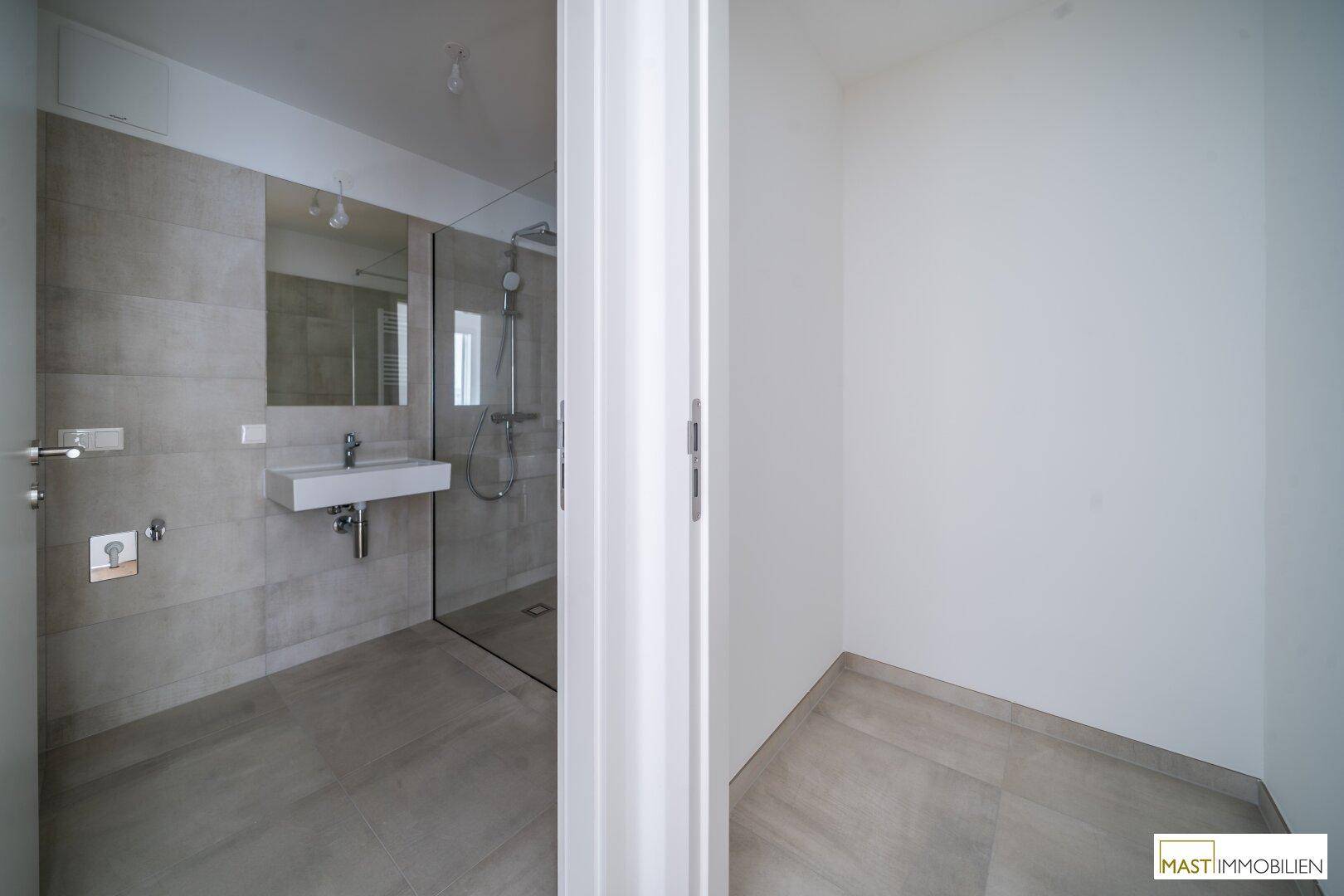 Blick in ein modernes Badezimmer mit begehbarer Dusche und eleganten Fliesen, das viel Platz bietet.