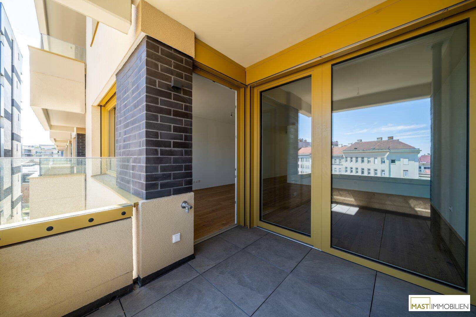 Geräumiger Balkon mit Fliesenboden und Zugang zum Wohnbereich, ideal für sonnige Tage.