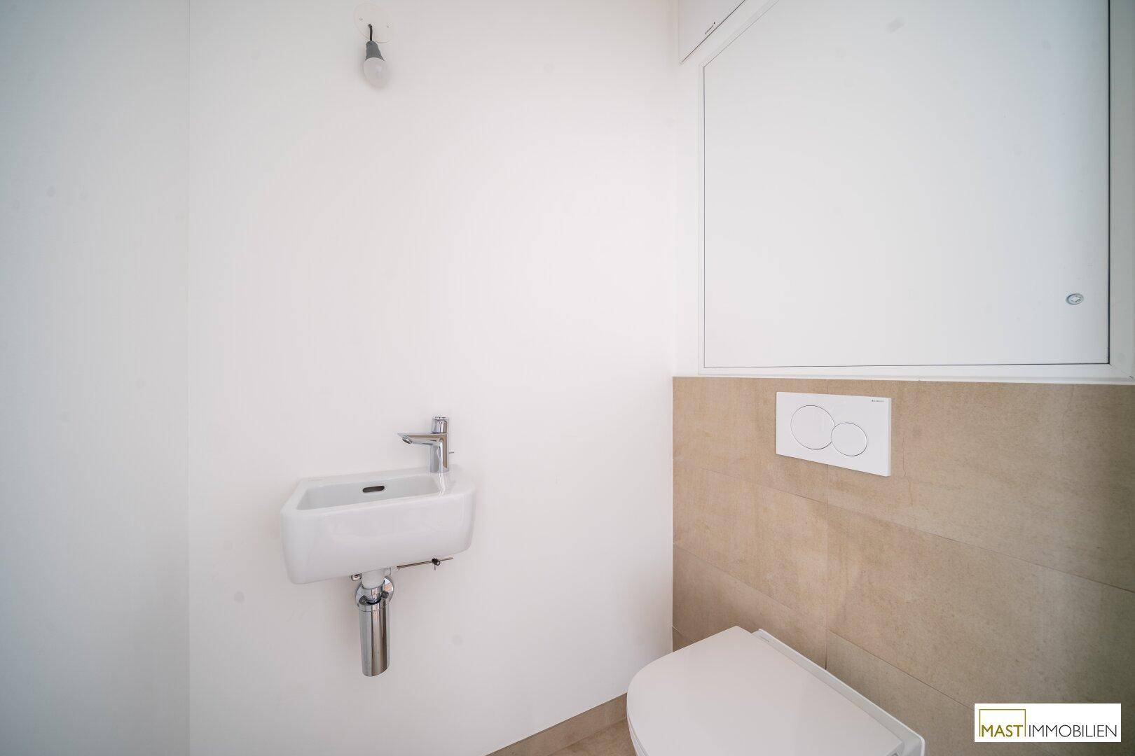 Modernes Gäste-WC mit Wand-WC, kleinem Waschbecken und stilvollen beigefarbenen Fliesen.
