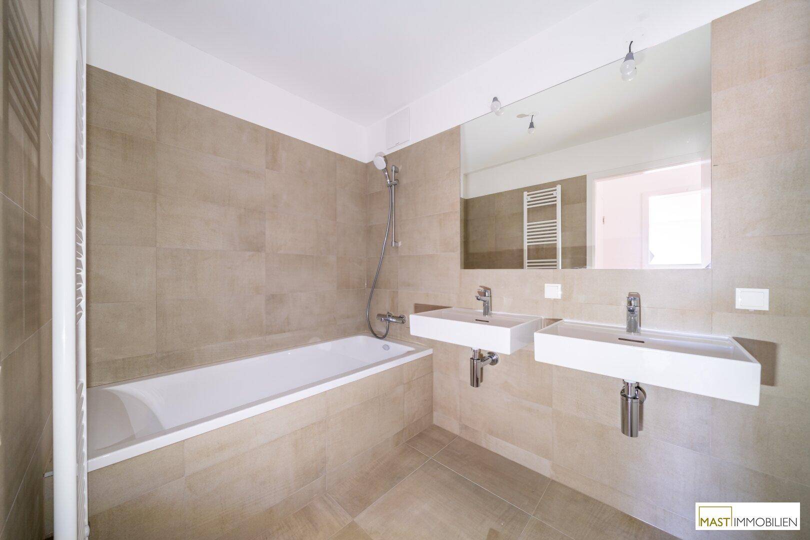 Modernes Badezimmer mit Badewanne, Doppelwaschbecken, großem Spiegel und beheiztem Handtuchhalter.