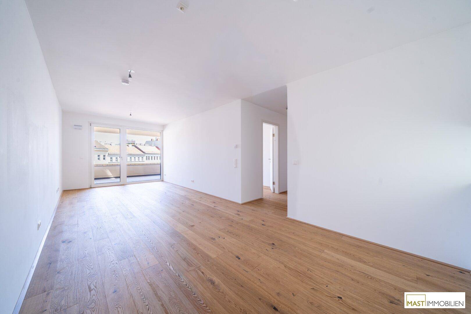 Heller, leerer Raum mit hochwertigem Parkettboden und direktem Zugang zu einem Balkon.