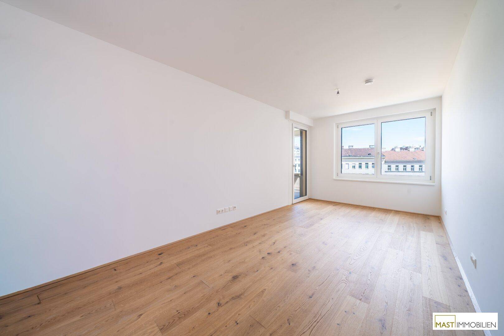 Heller Raum mit Hartholzboden und großem Fenster, bietet einen weiten Blick auf die Stadt.