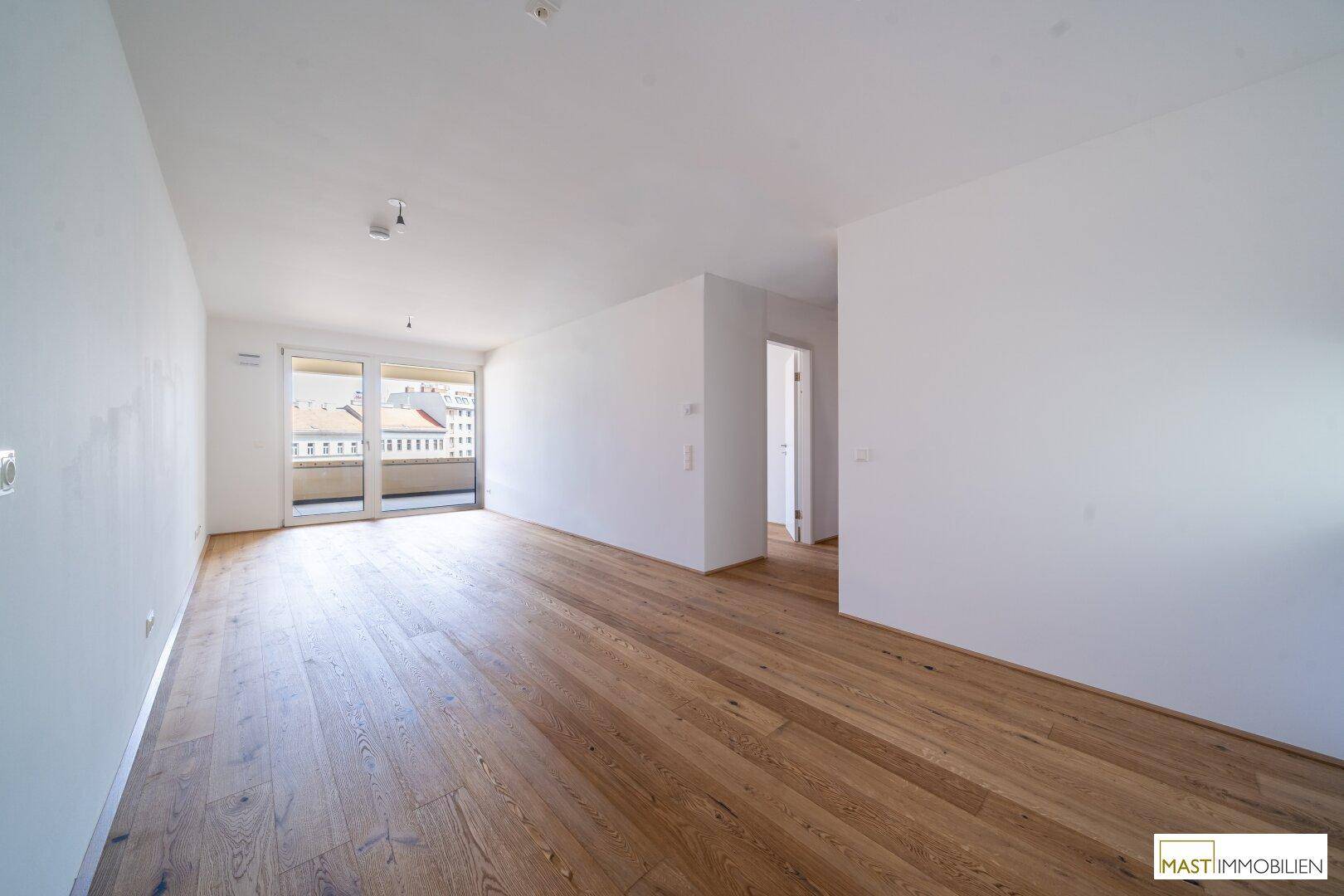 Geräumiger, heller Raum mit Hartholzboden und großem Schiebetürzugang zu einem Balkon.