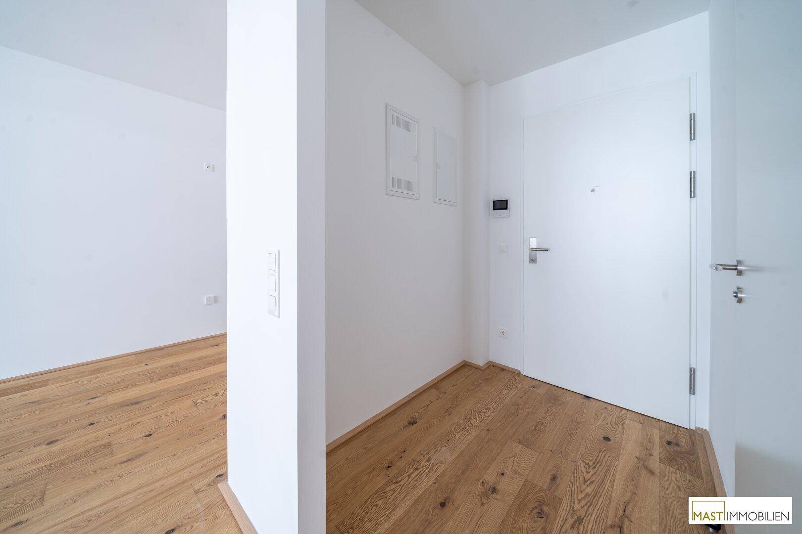 Heller Eingangsbereich mit Holzboden und weißen Wänden, der einen modernen und sauberen Eindruck vermittelt.