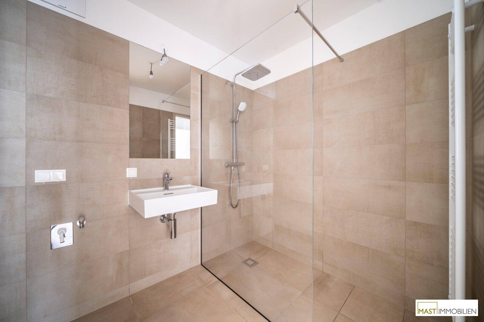 Modernes Badezimmer mit ebenerdiger Dusche, beigefarbenen Fliesen und minimalistischem Design.