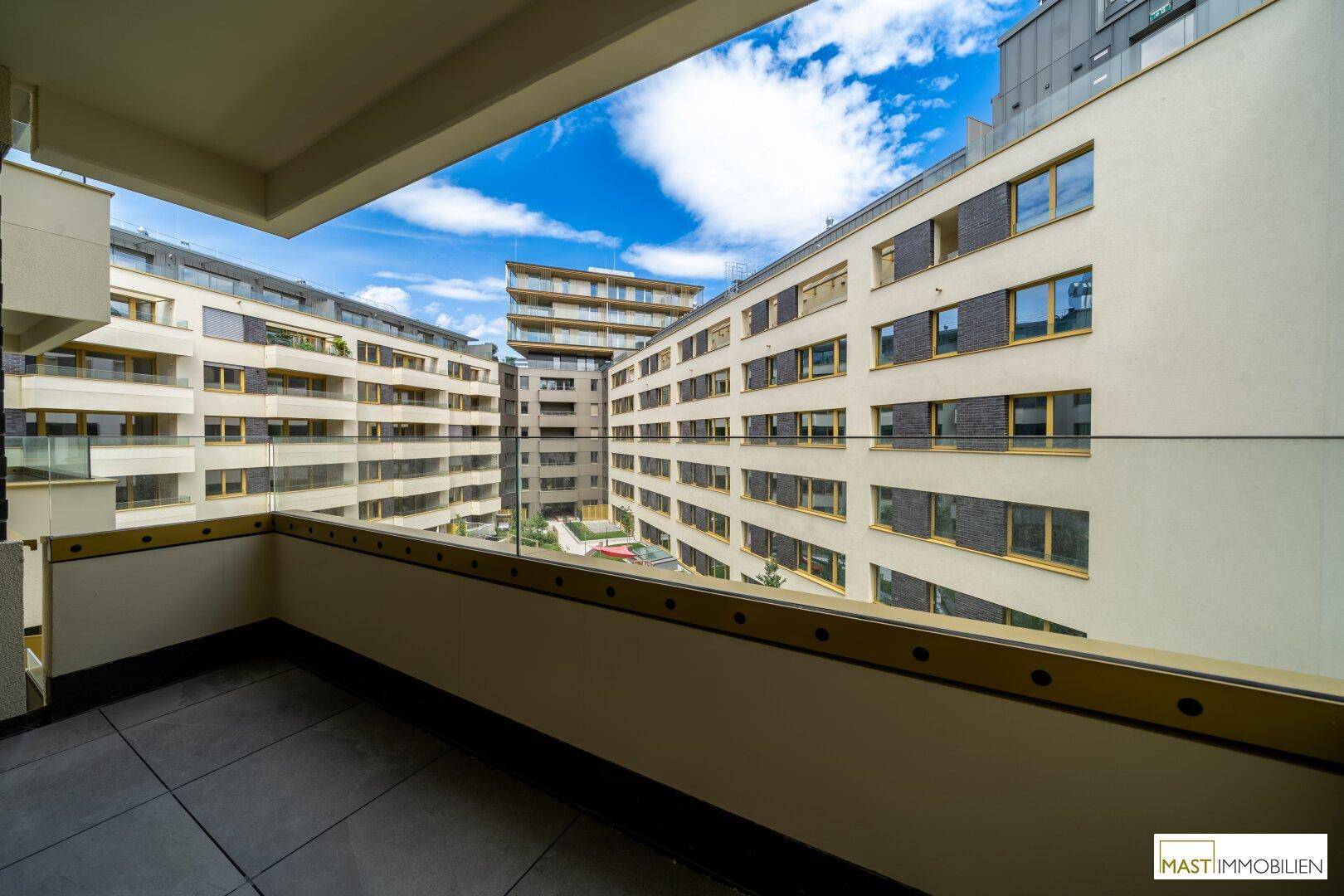 Balkon mit weitem Blick auf den modernen Innenhof und die umliegenden Wohngebäude.