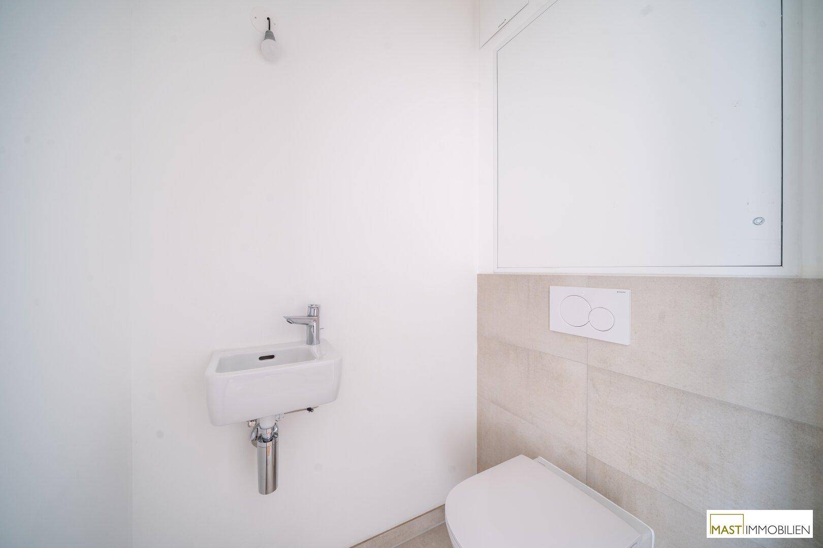 Modernes Gäste-WC mit kleinem Waschbecken und Wand-WC, in neutralen Farbtönen gehalten.