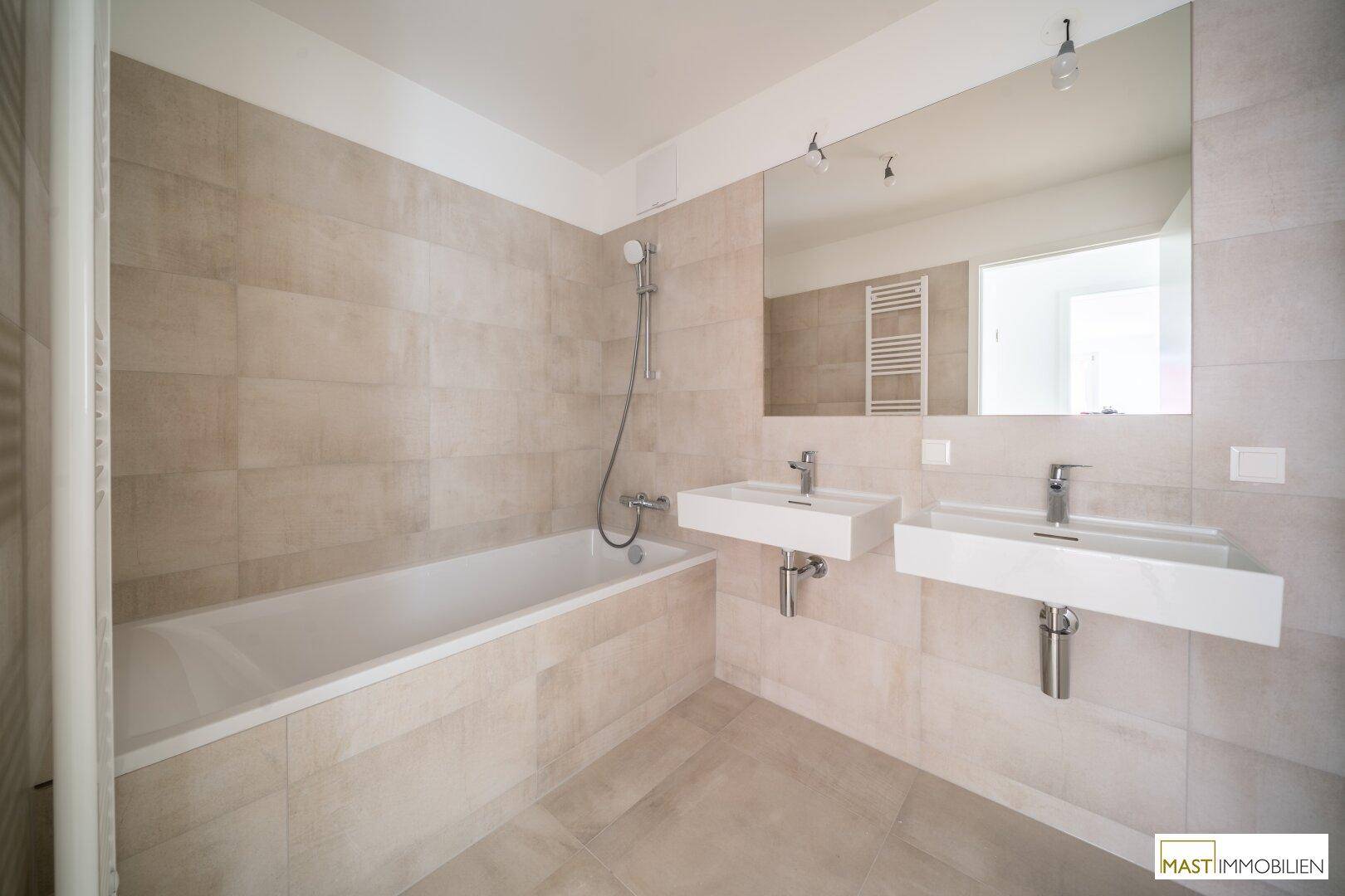 Modernes Badezimmer mit Doppelwaschbecken, Badewanne und beheiztem Handtuchhalter.