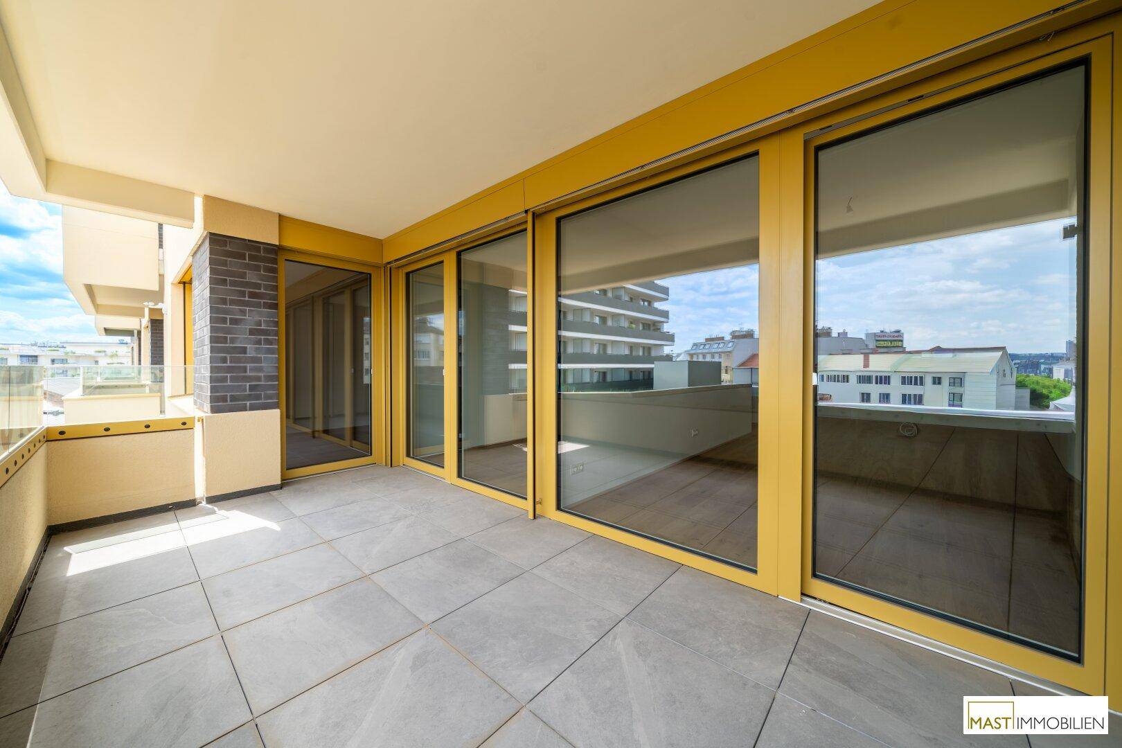 Breiter Balkon mit großen Schiebetüren, die viel Licht in die Innenräume lassen.