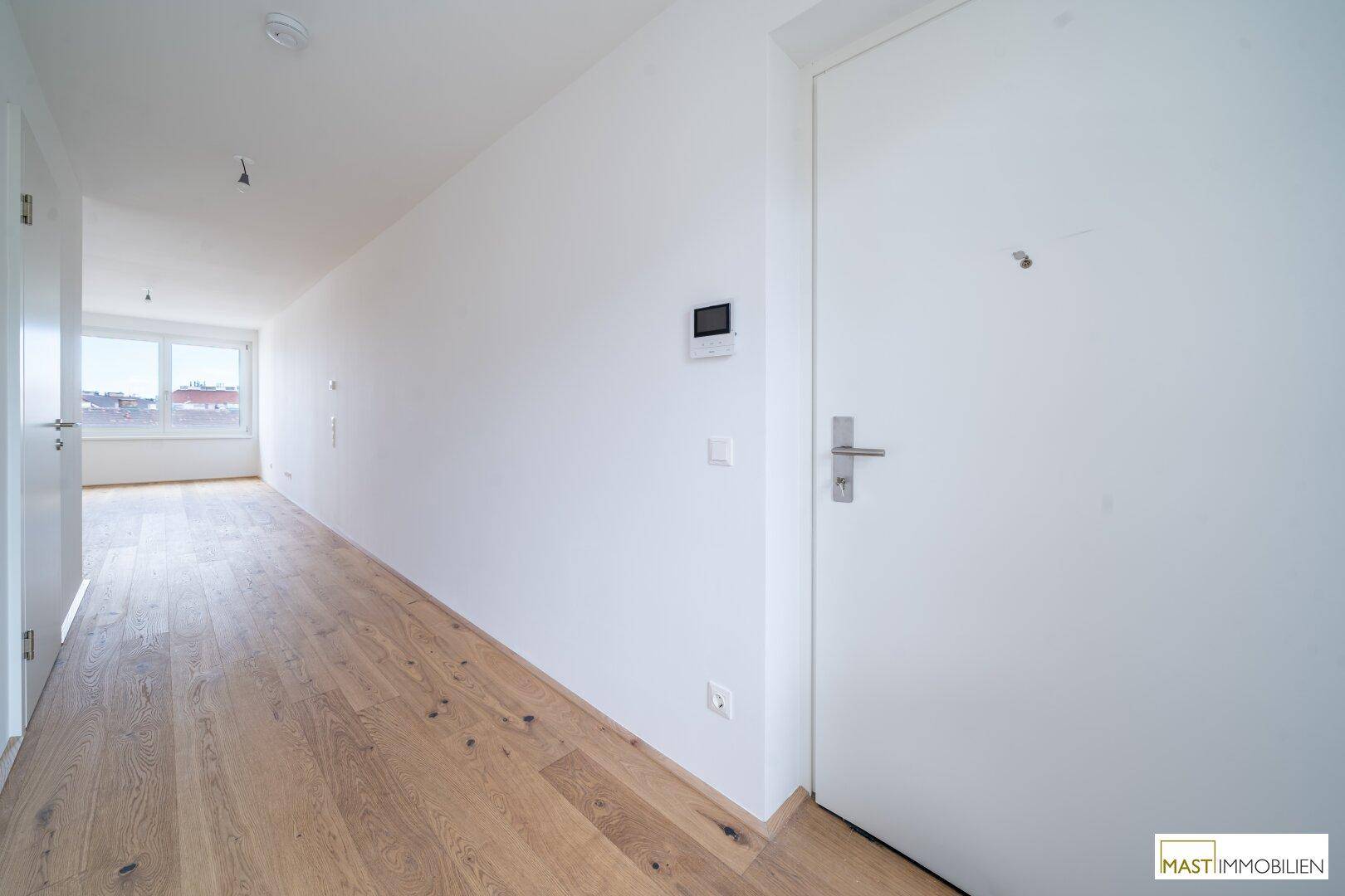 Geräumiger Flur mit Holzboden und weiß gestrichenen Wänden, einladender Eingangsbereich.
