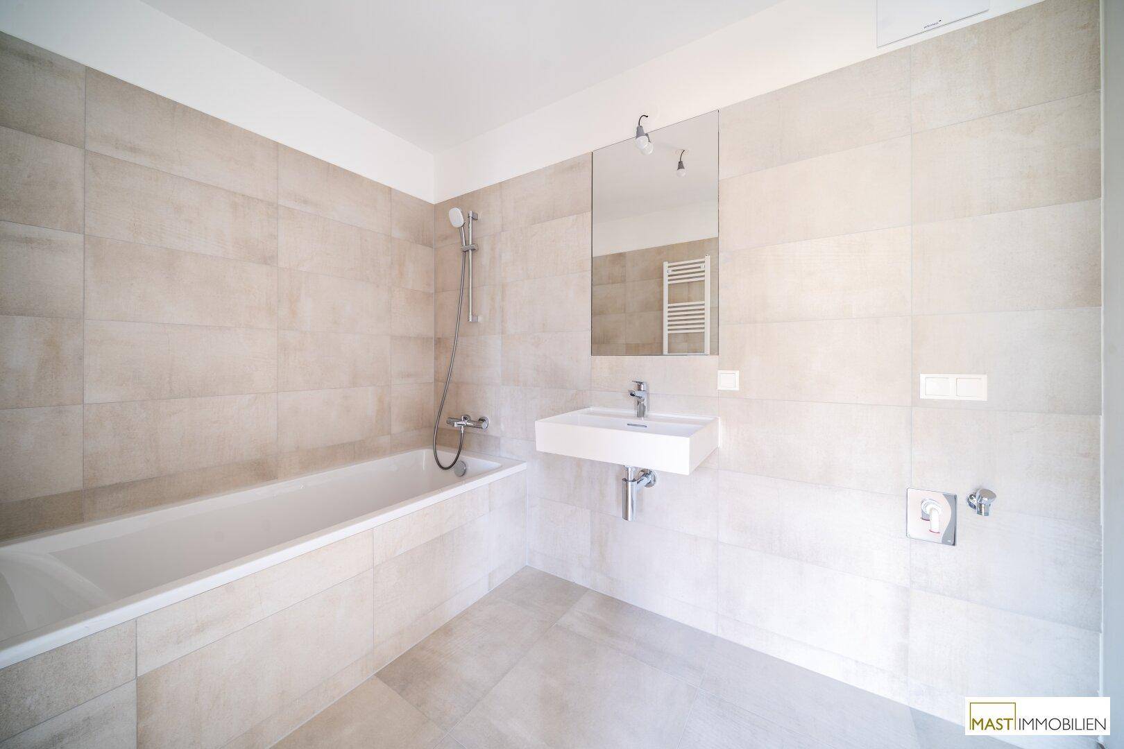 Helles Badezimmer mit Badewanne, modernem Waschbecken und beheiztem Handtuchhalter.