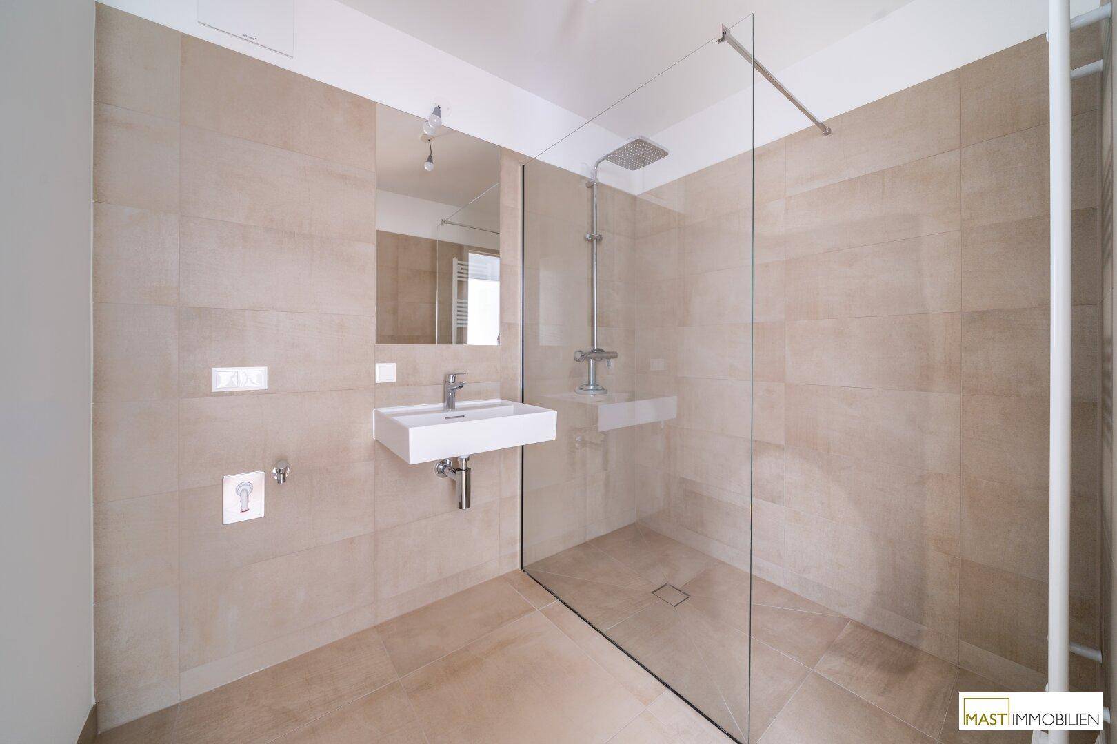 Modernes Badezimmer mit großer begehbarer Dusche, Regenbrause und beigefarbenen Wand- und Bodenfliesen.