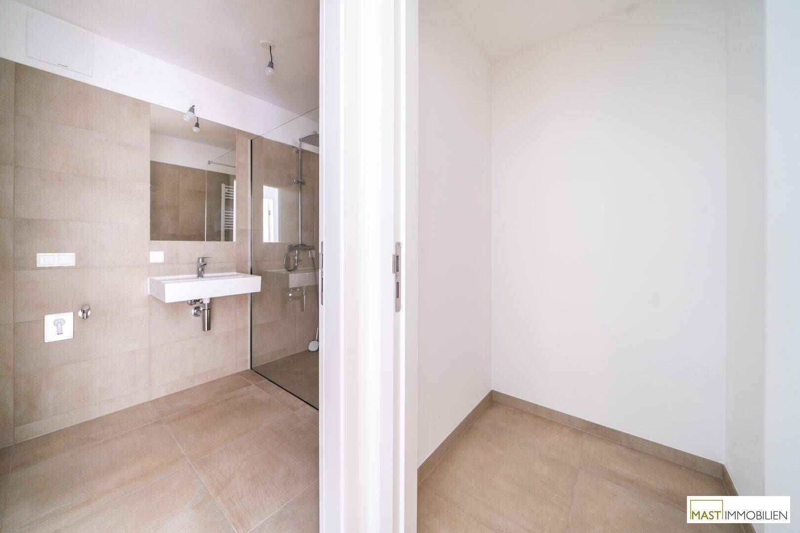 Teilansicht eines modernen Badezimmers mit Dusche und angrenzendem, leeren Raum.