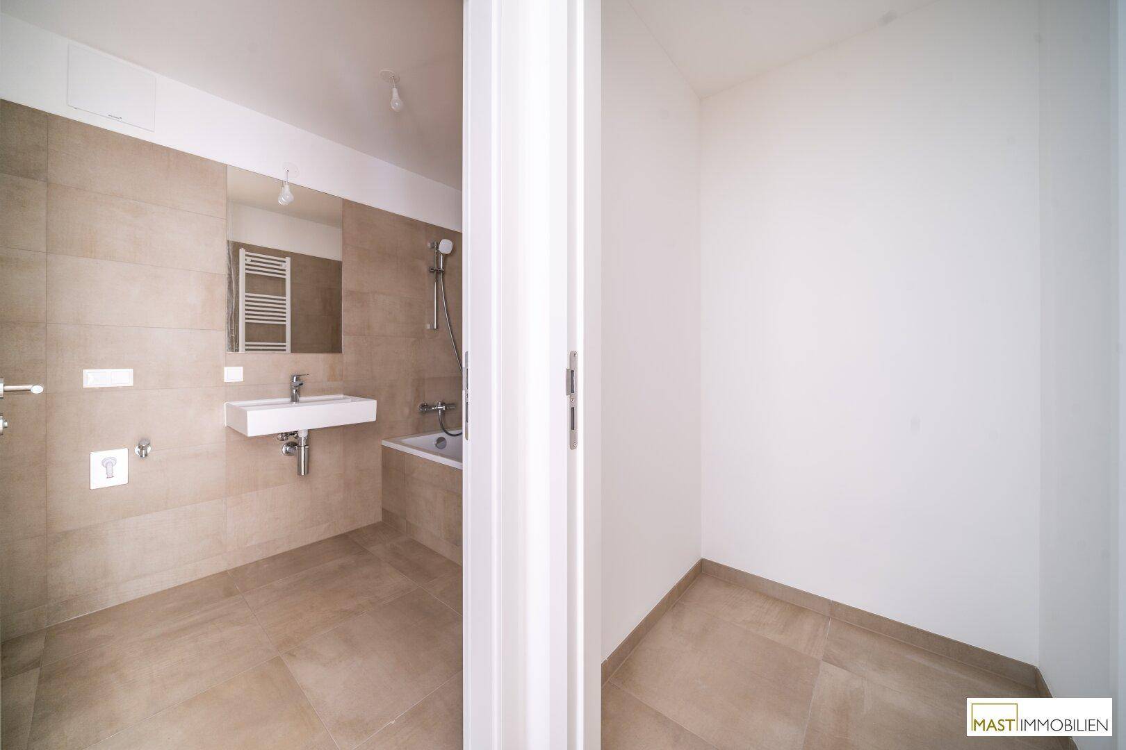 Badezimmer mit beigefarbenen Fliesen, modernem Waschbecken und Badewanne.