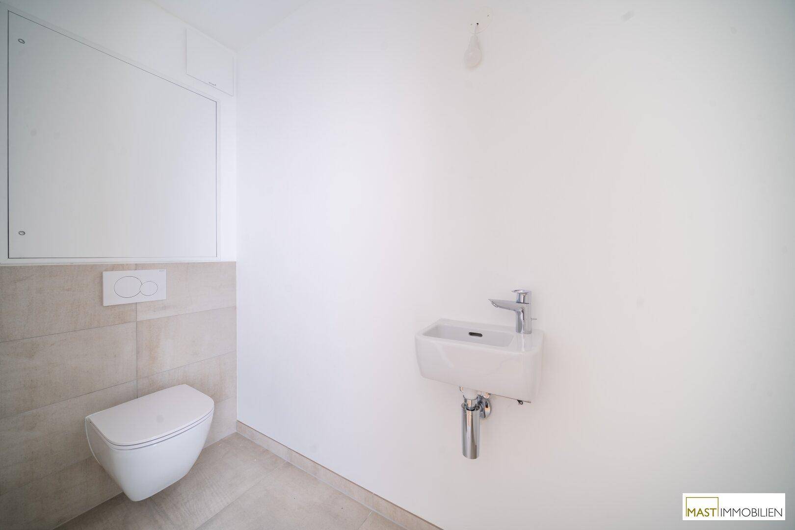 Modernes Gäste-WC mit wandhängender Toilette und kleinem Waschbecken, in hellen Farbtönen gehalten.
