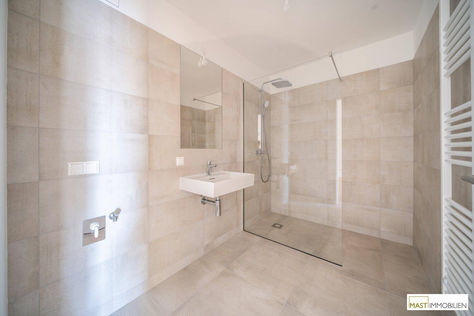 Modernes Badezimmer mit ebenerdiger Dusche, elegantem Waschbecken und beheiztem Handtuchhalter.