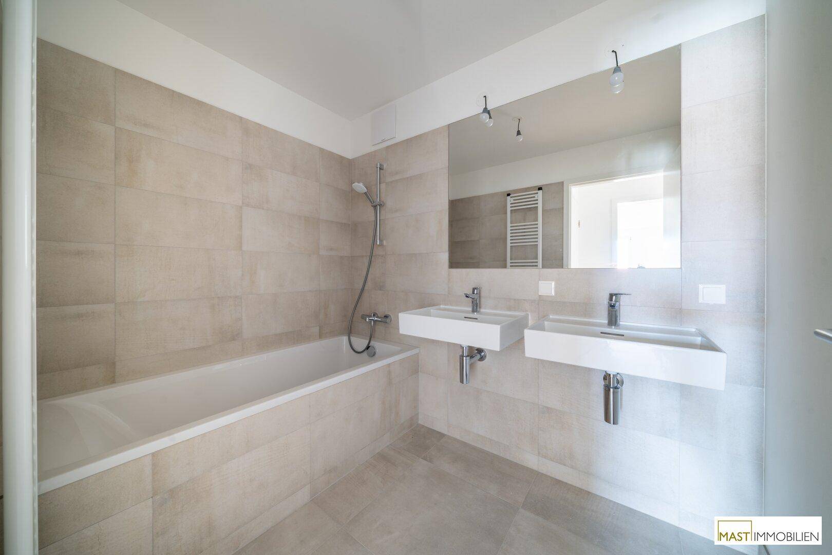 Modernes Badezimmer mit Badewanne, Doppelwaschbecken und großem Spiegel.