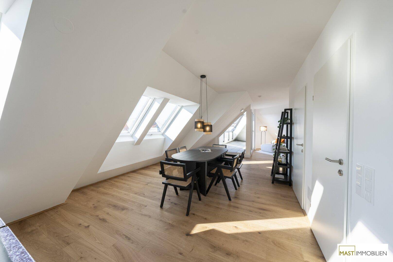 Heller Essbereich mit Holzboden und modernen Möbeln, beleuchtet durch schräge Dachfenster.