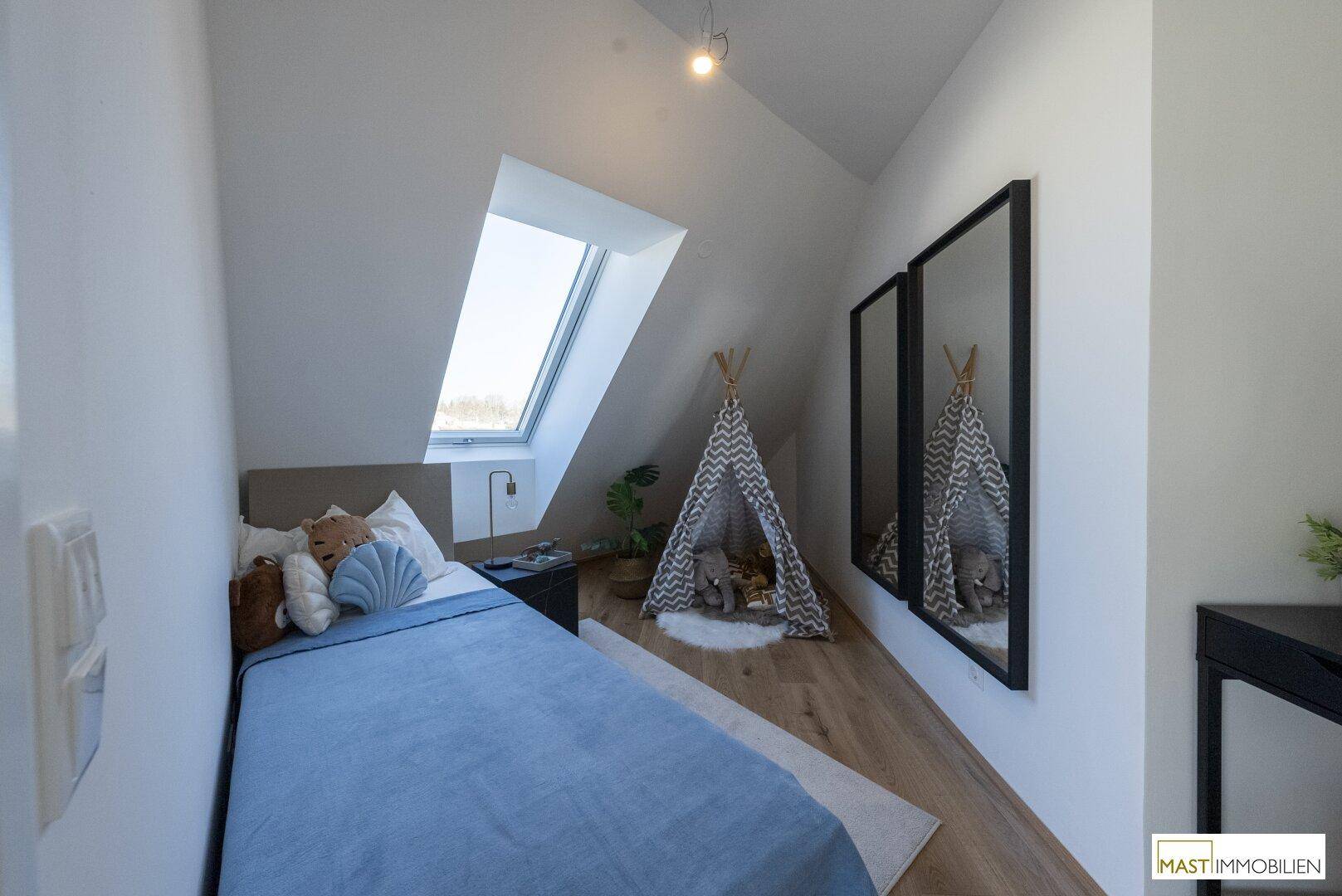 Gemütliches Schlafzimmer mit Holzboden, Dachfenster und modernem Dekor, ideal für ein Kinderzimmer.