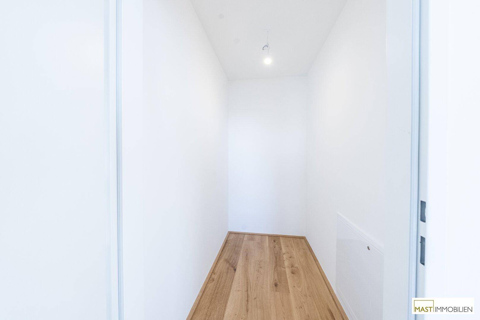 Kleiner, heller Abstellraum mit Holzboden und weißen Wänden, ideal für zusätzlichen Stauraum.