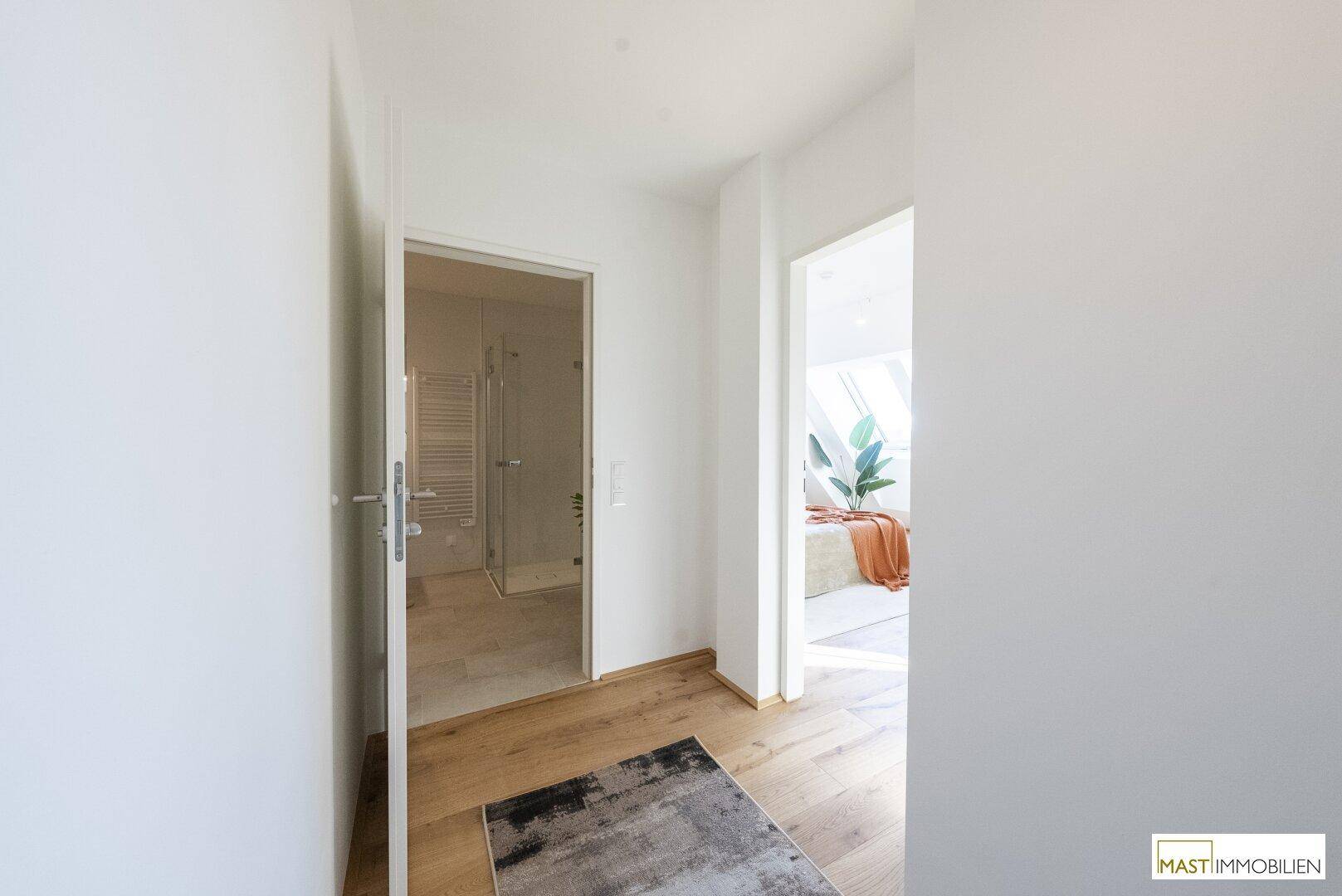 Heller Flur mit Holzboden, der den Zugang zu Bad und Schlafzimmer ermöglicht.