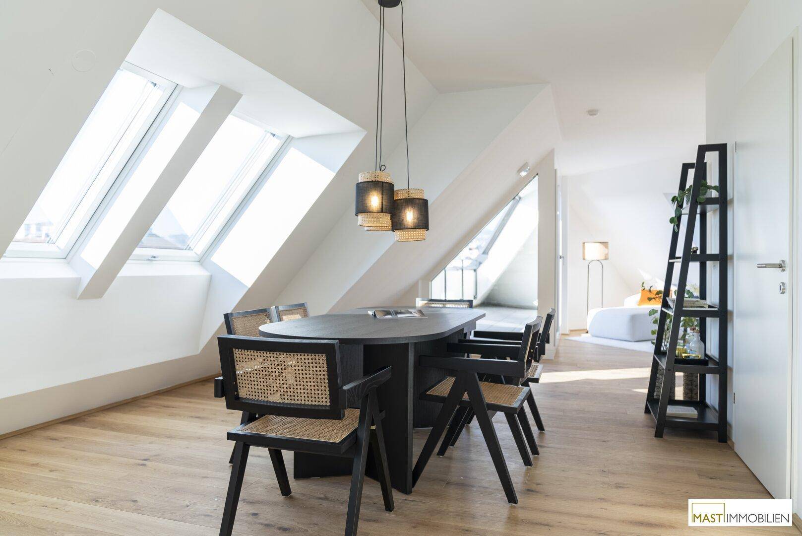Moderner Essbereich mit Holzboden, dunklem Esstisch und stilvollen Hängelampen unter schrägen Decken.